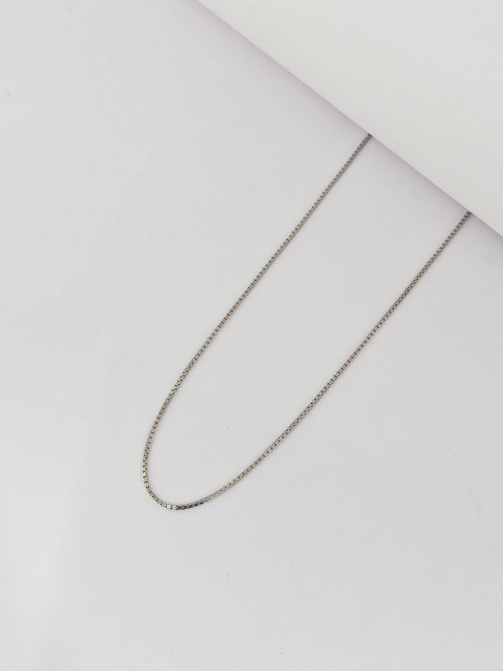 Silver chain necklace on a light gray background