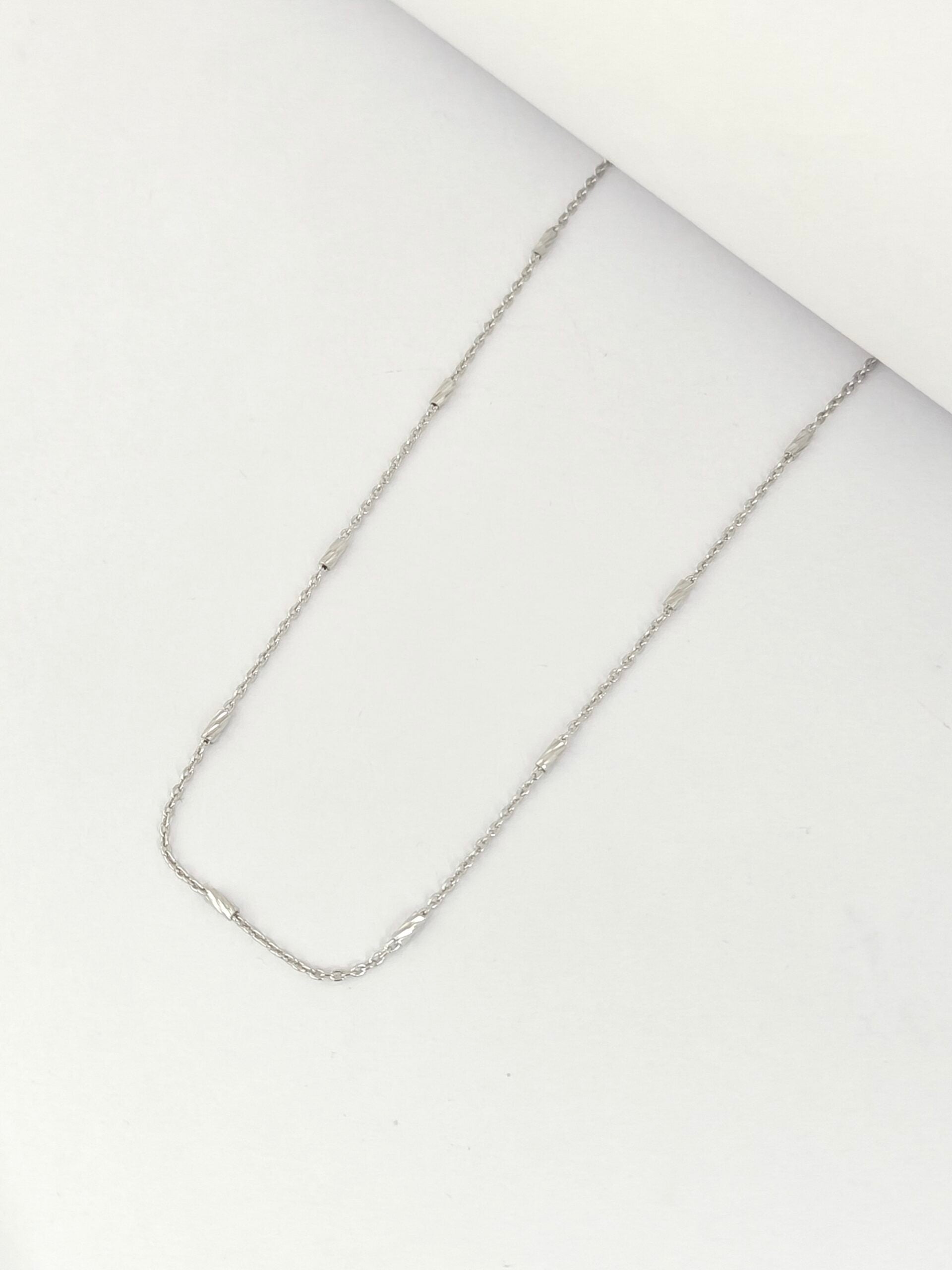 Silver chain necklace on a white surface
