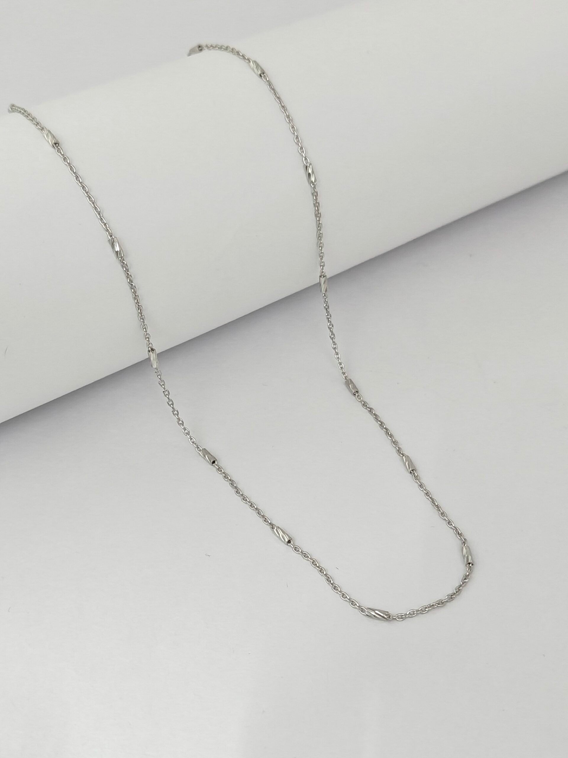 Silver chain necklace on a light gray background