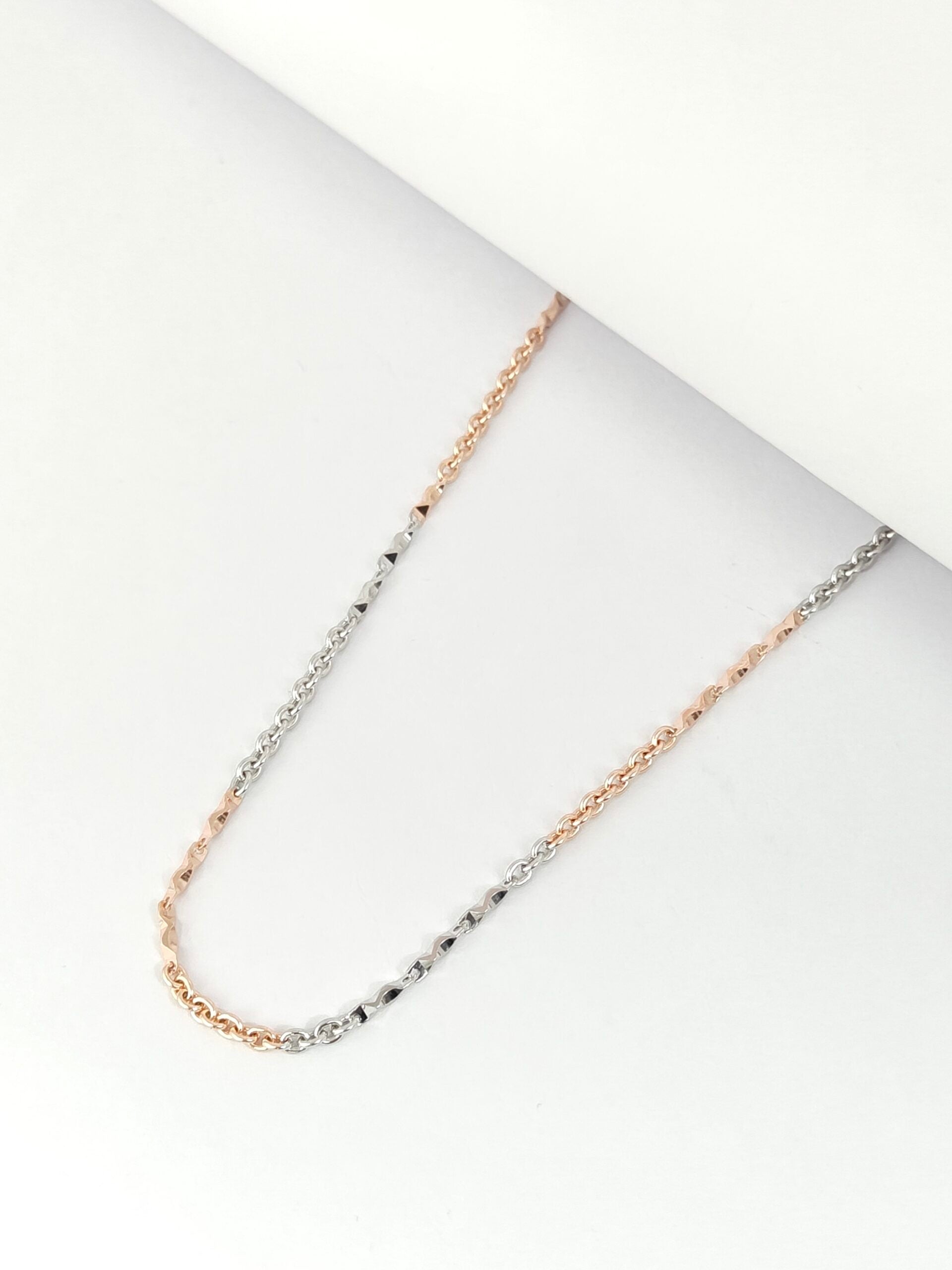 Necklace with rose gold and silver chain on a white surface