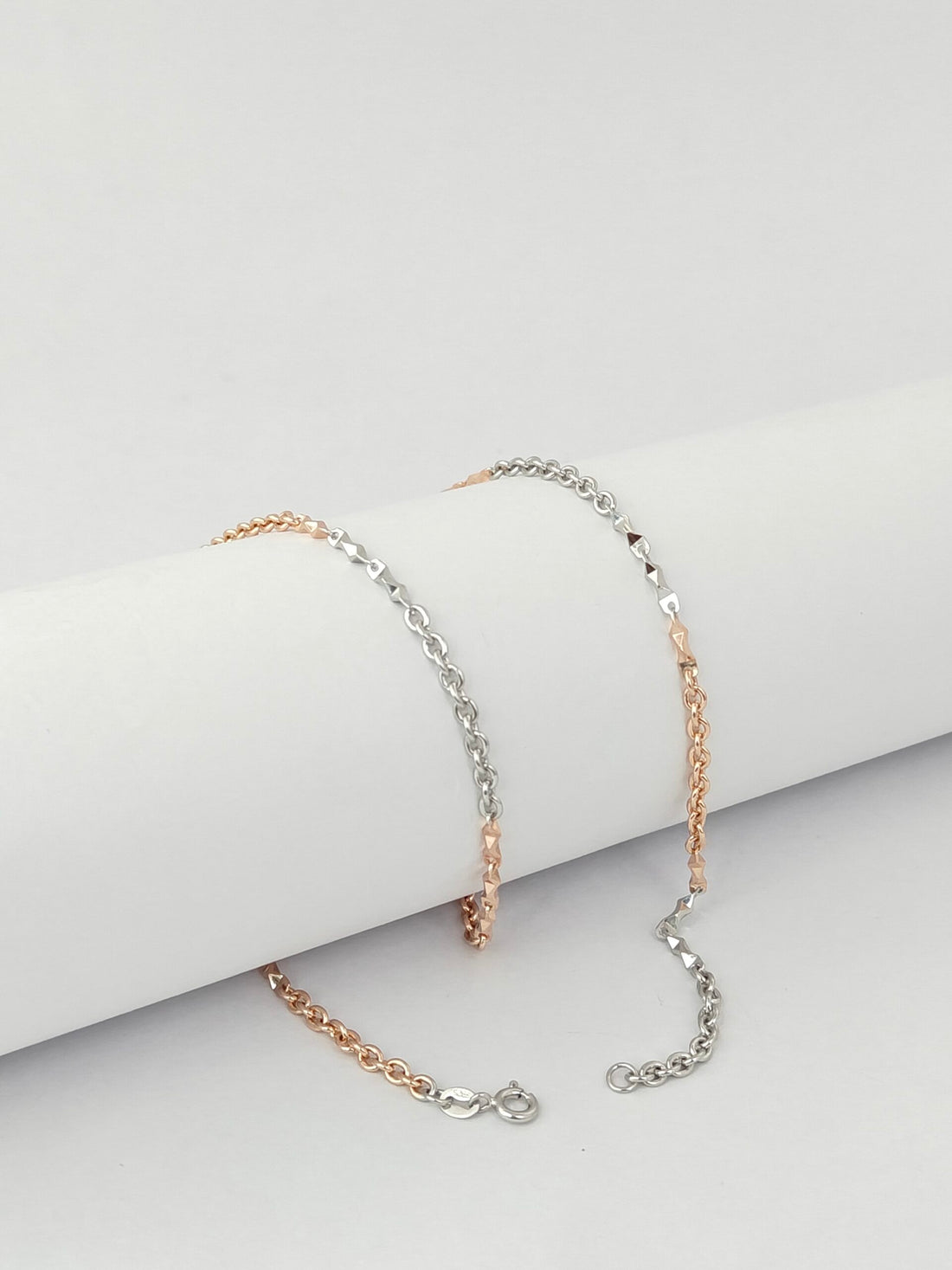 Two chain necklaces on a light gray surface