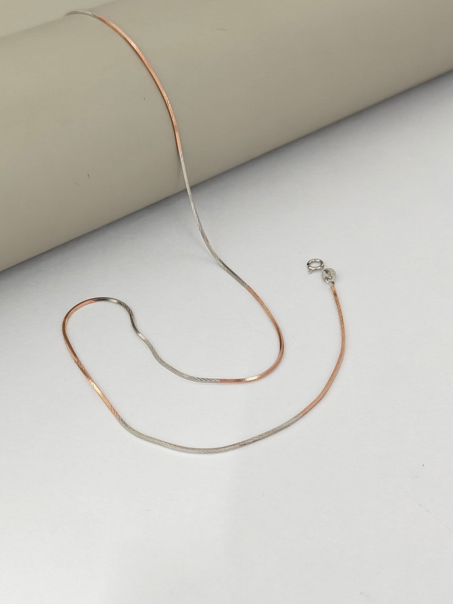 Gold necklace on a light gray surface