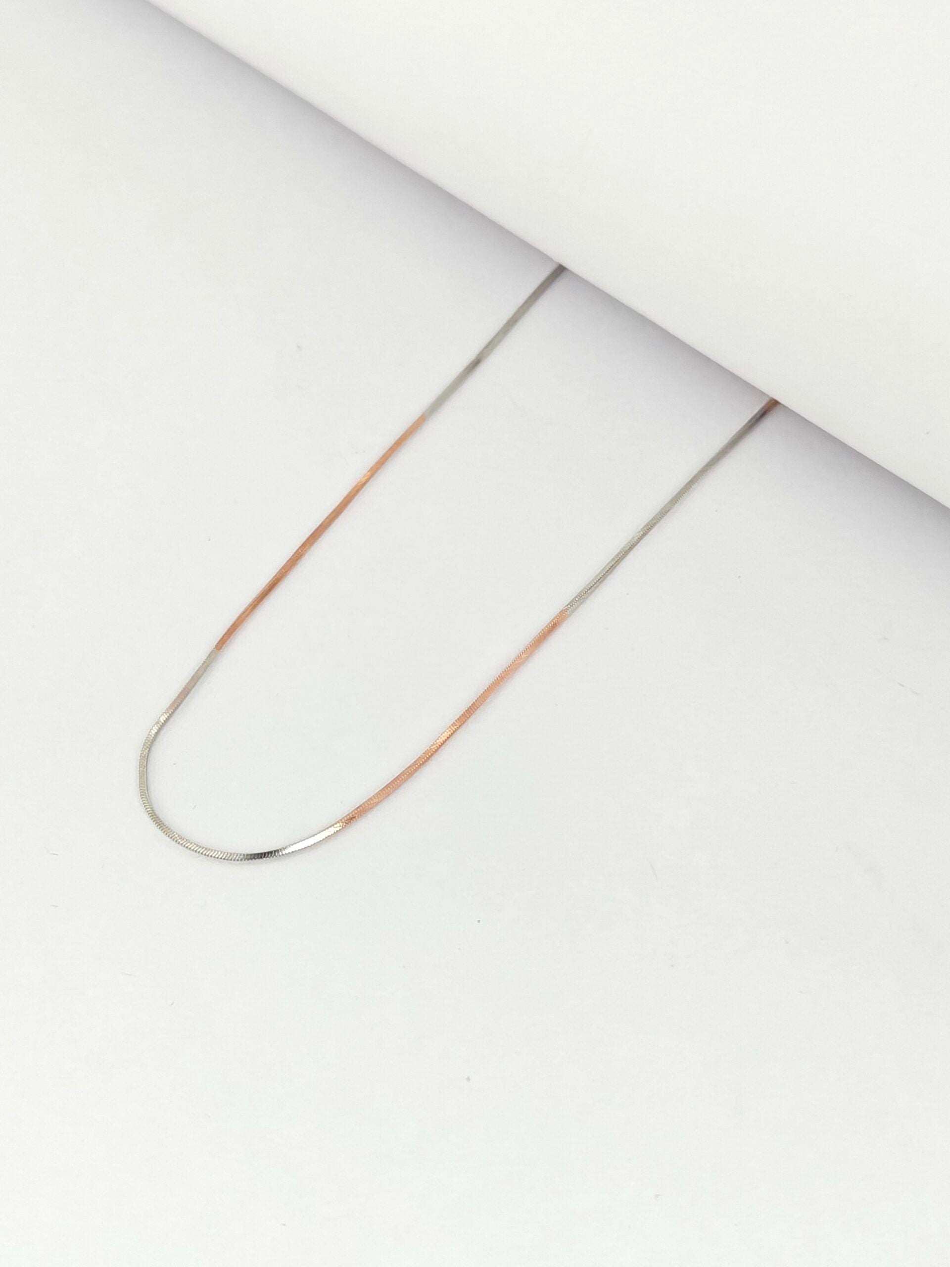 Thin gold chain on a white background