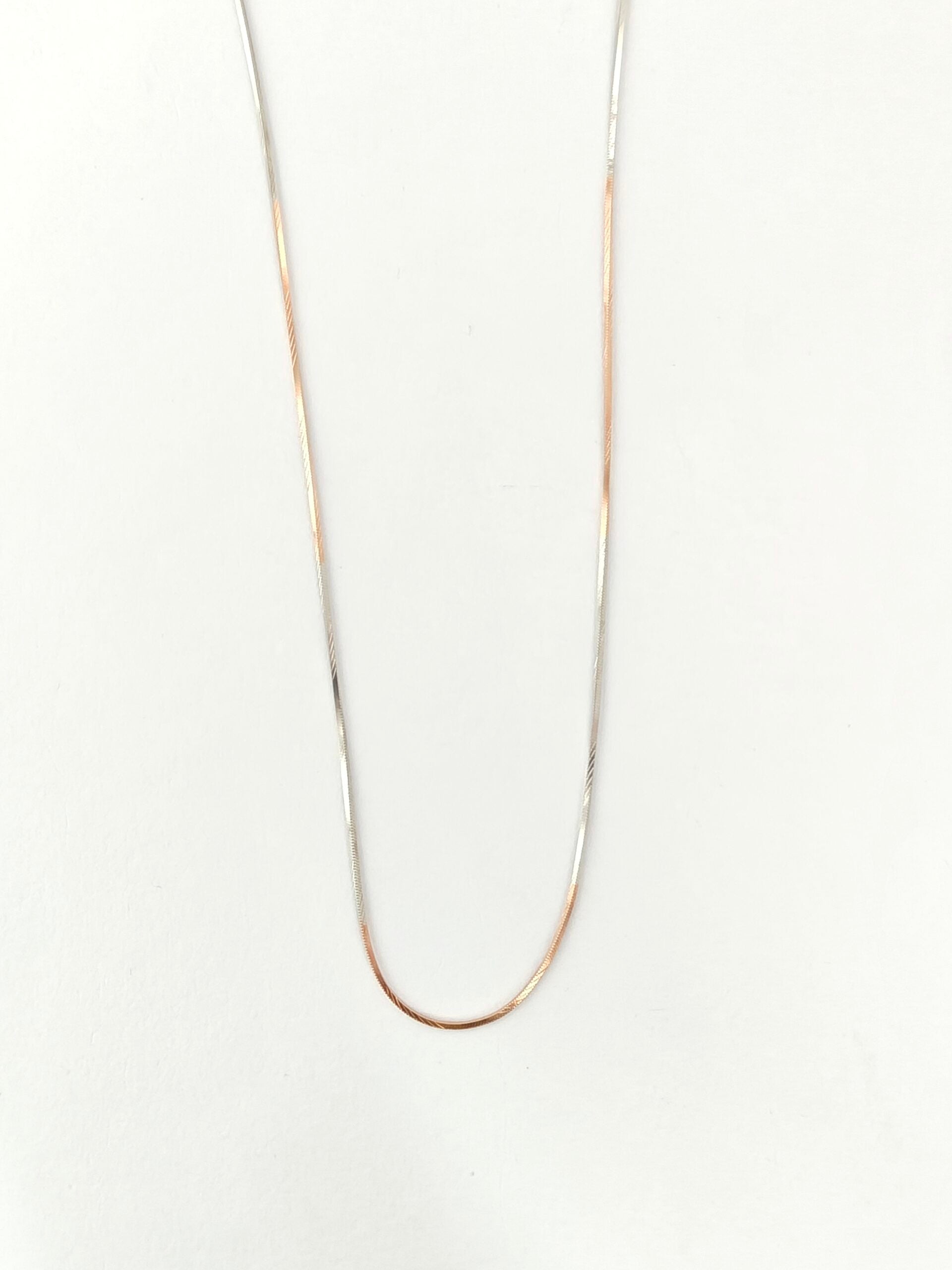 Thin gold necklace on a white background
