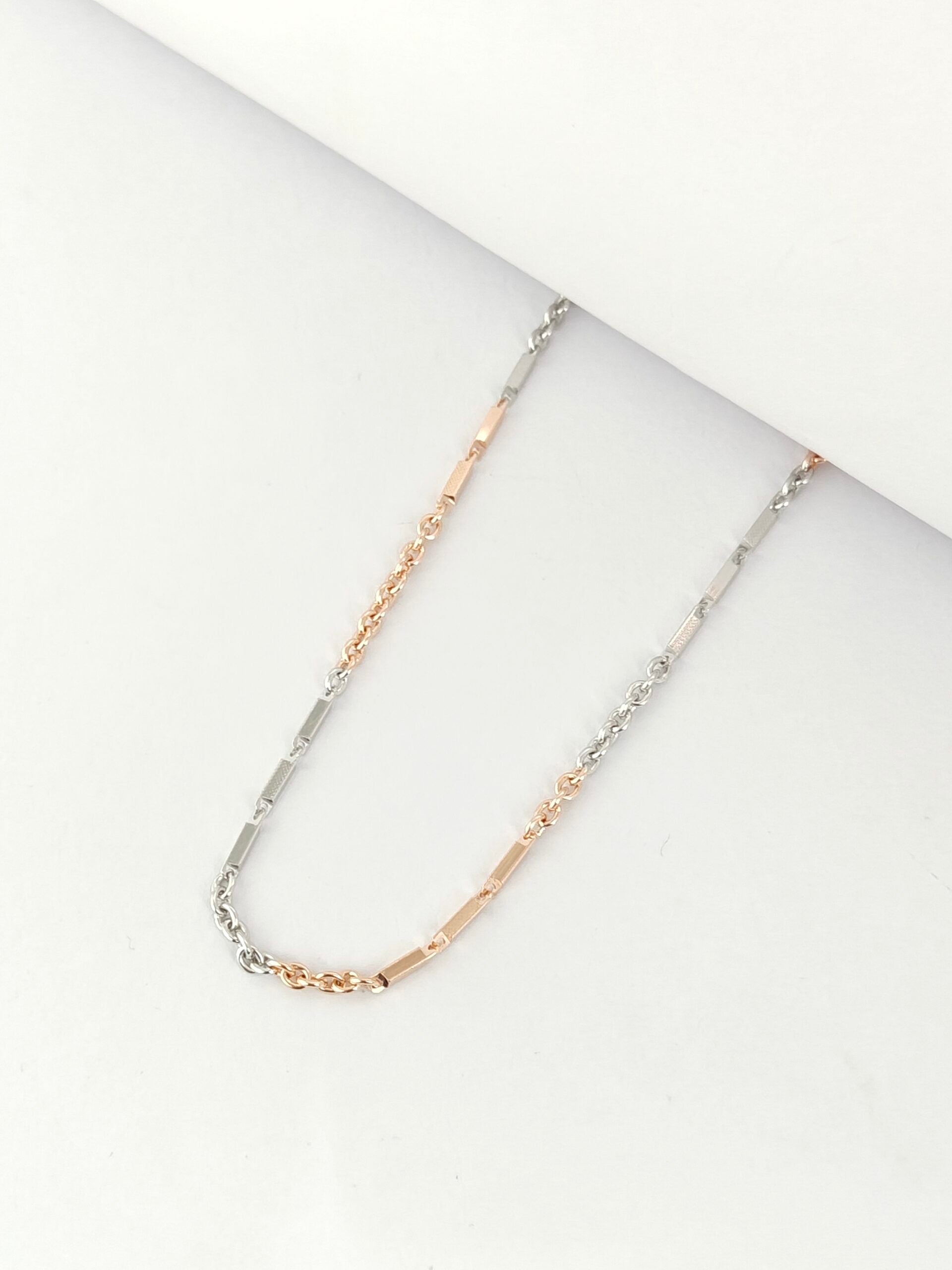 Two-tone gold and silver chain necklace on a white surface