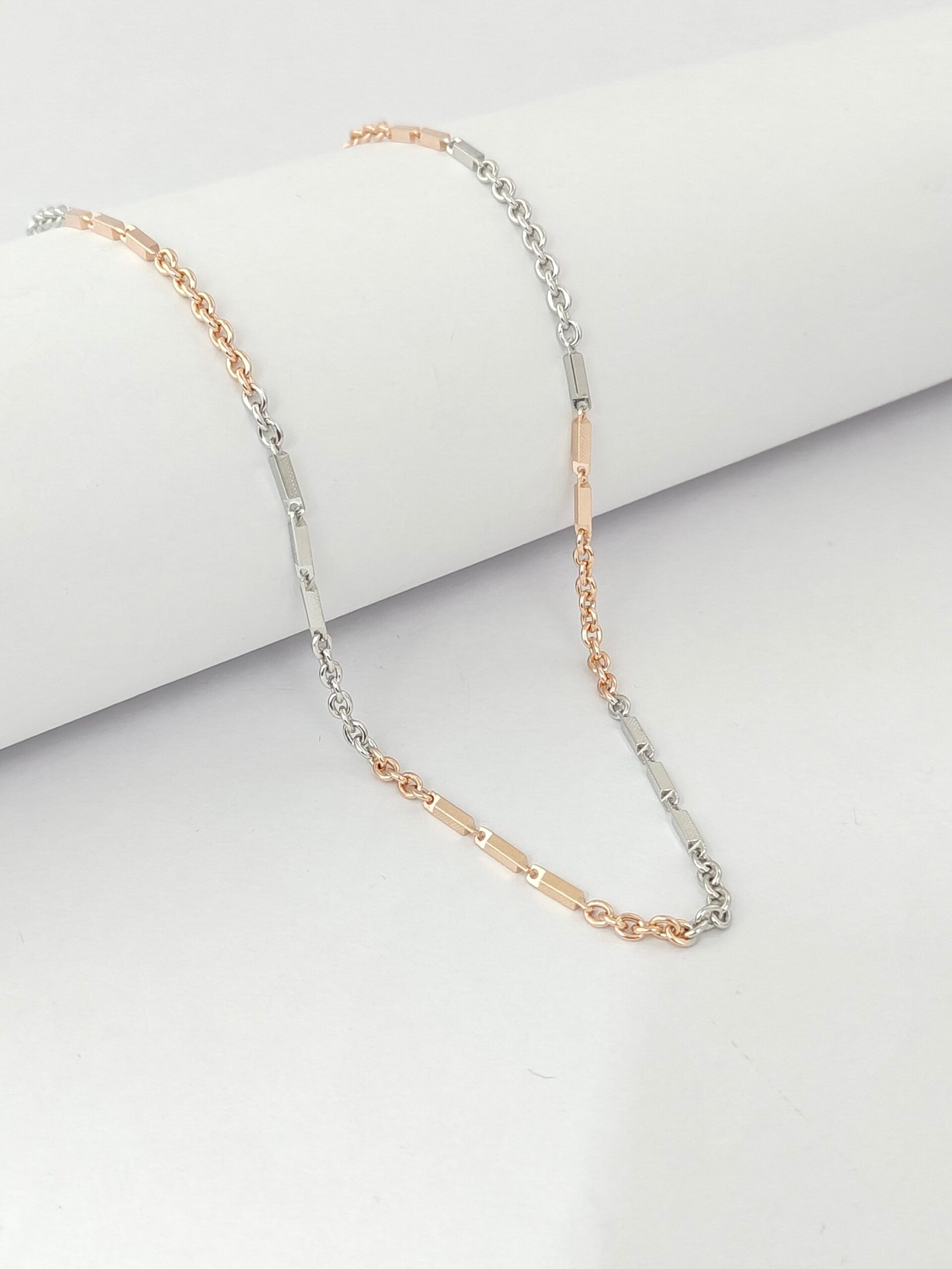 Two gold necklaces on a light gray background