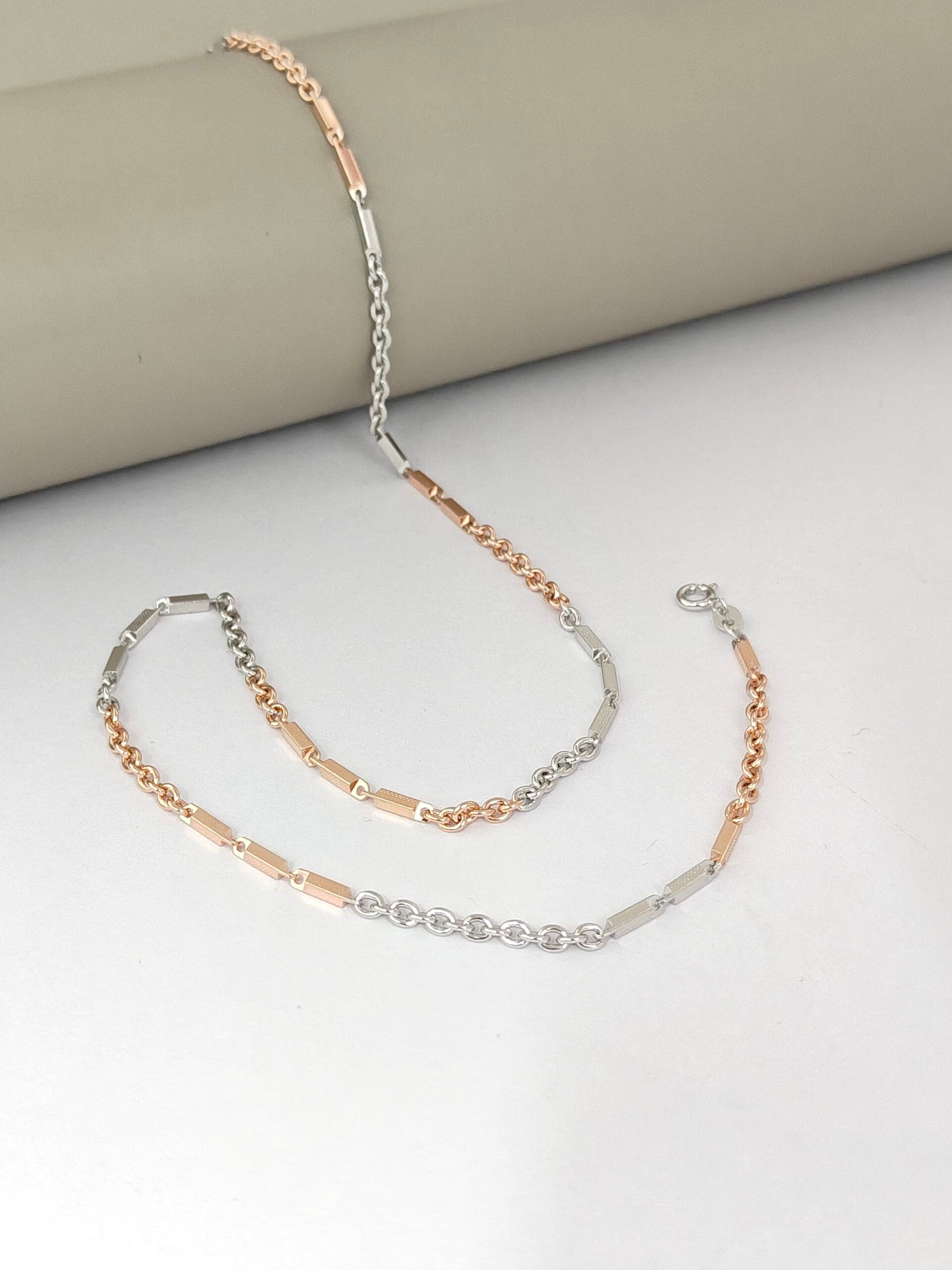 Two layered gold and silver necklaces on a light gray surface.