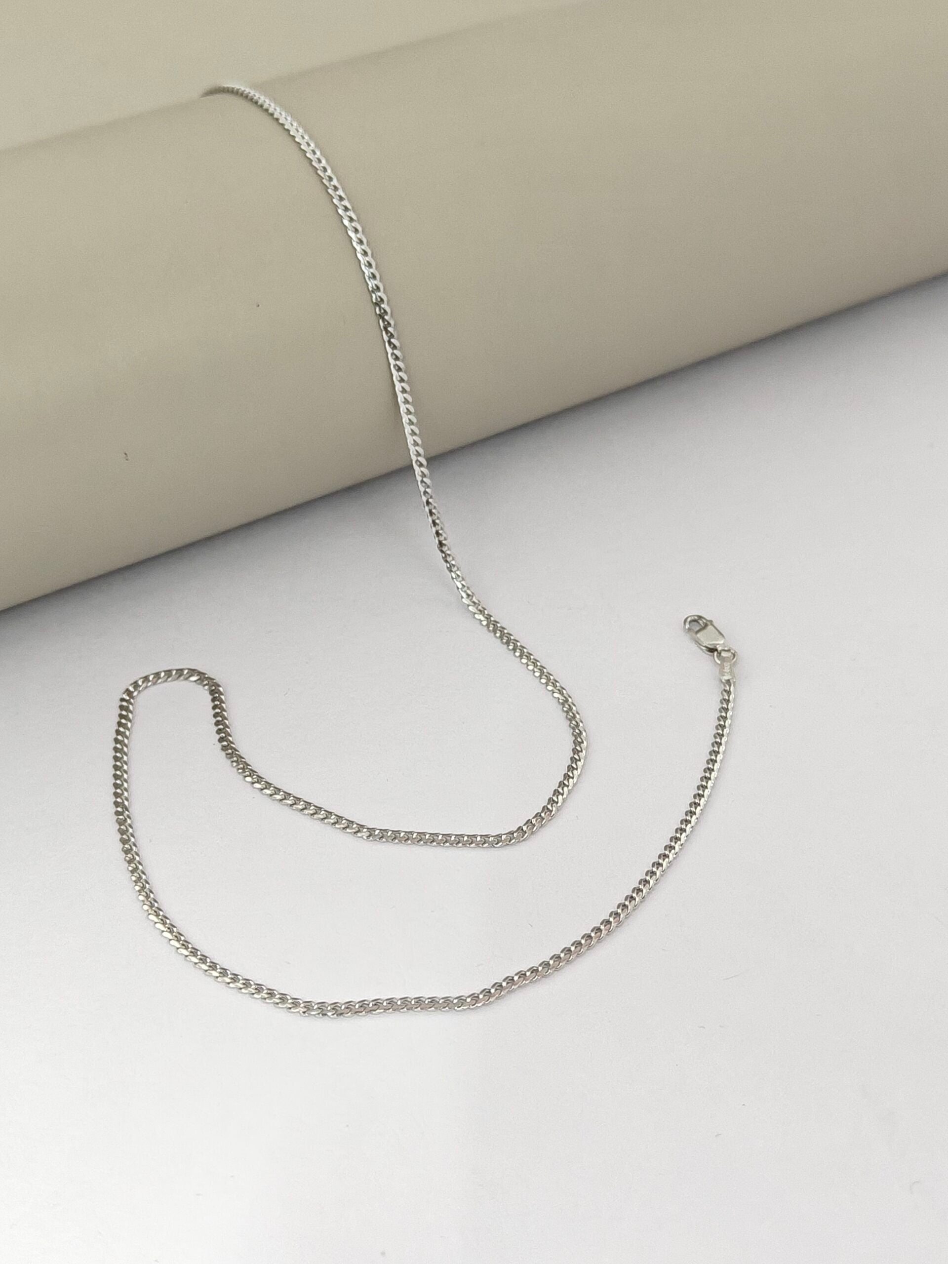 Silver chain necklace on a light gray surface