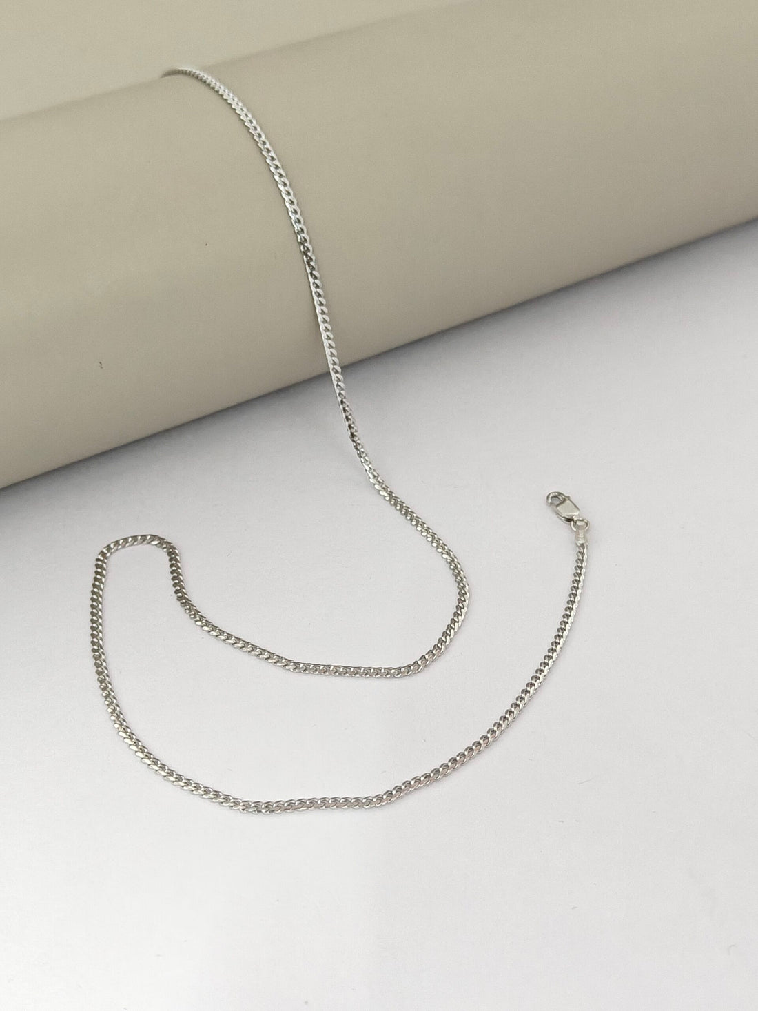 Silver chain necklace on a light gray surface