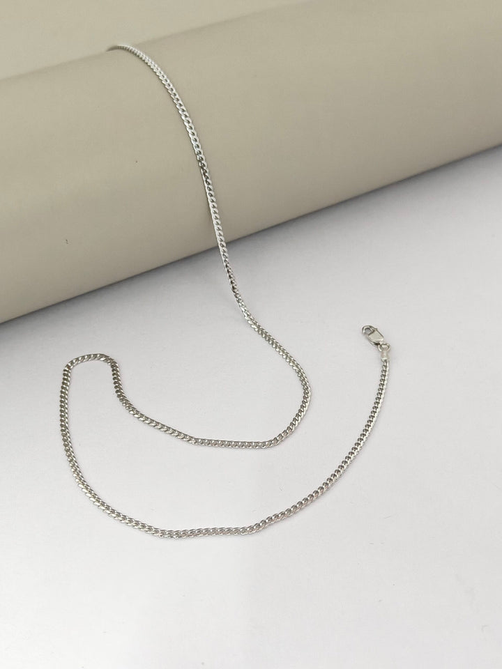 Silver chain necklace on a light gray surface
