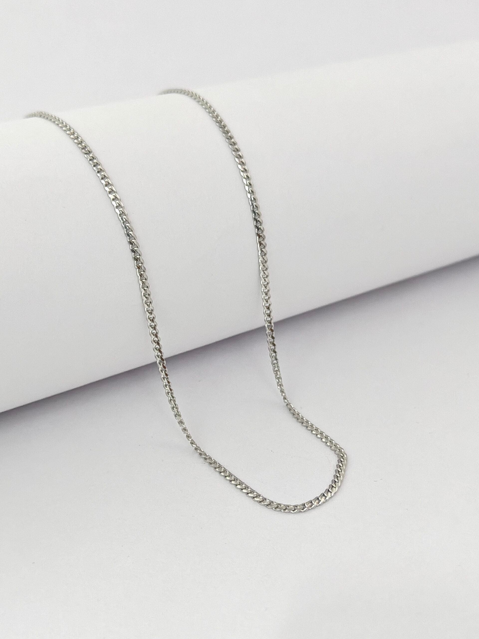 Silver chain necklace on a light gray background