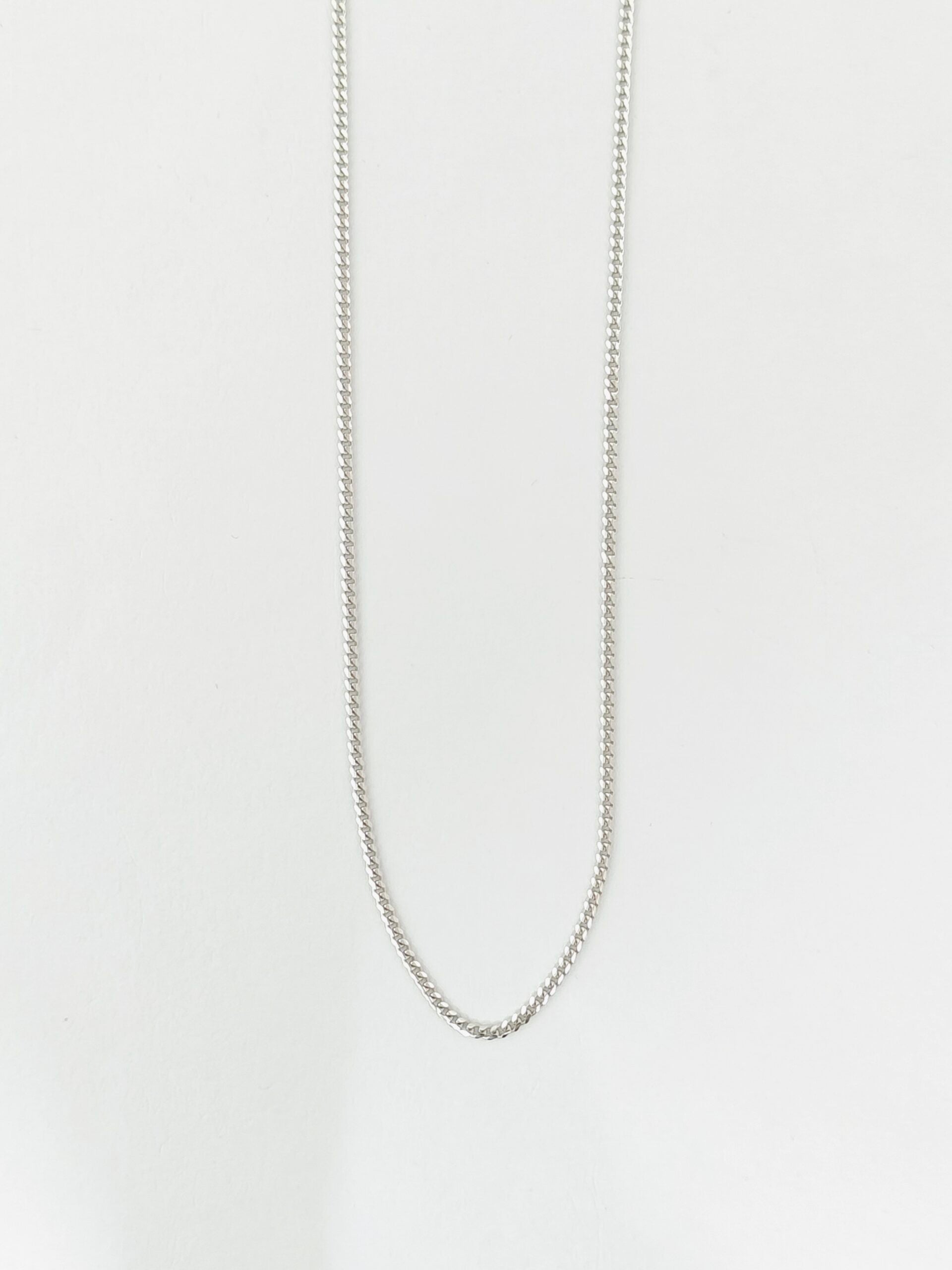 Silver chain necklace on a light gray background