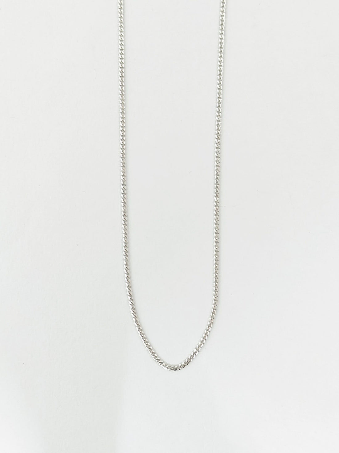 Silver chain necklace on a light gray background