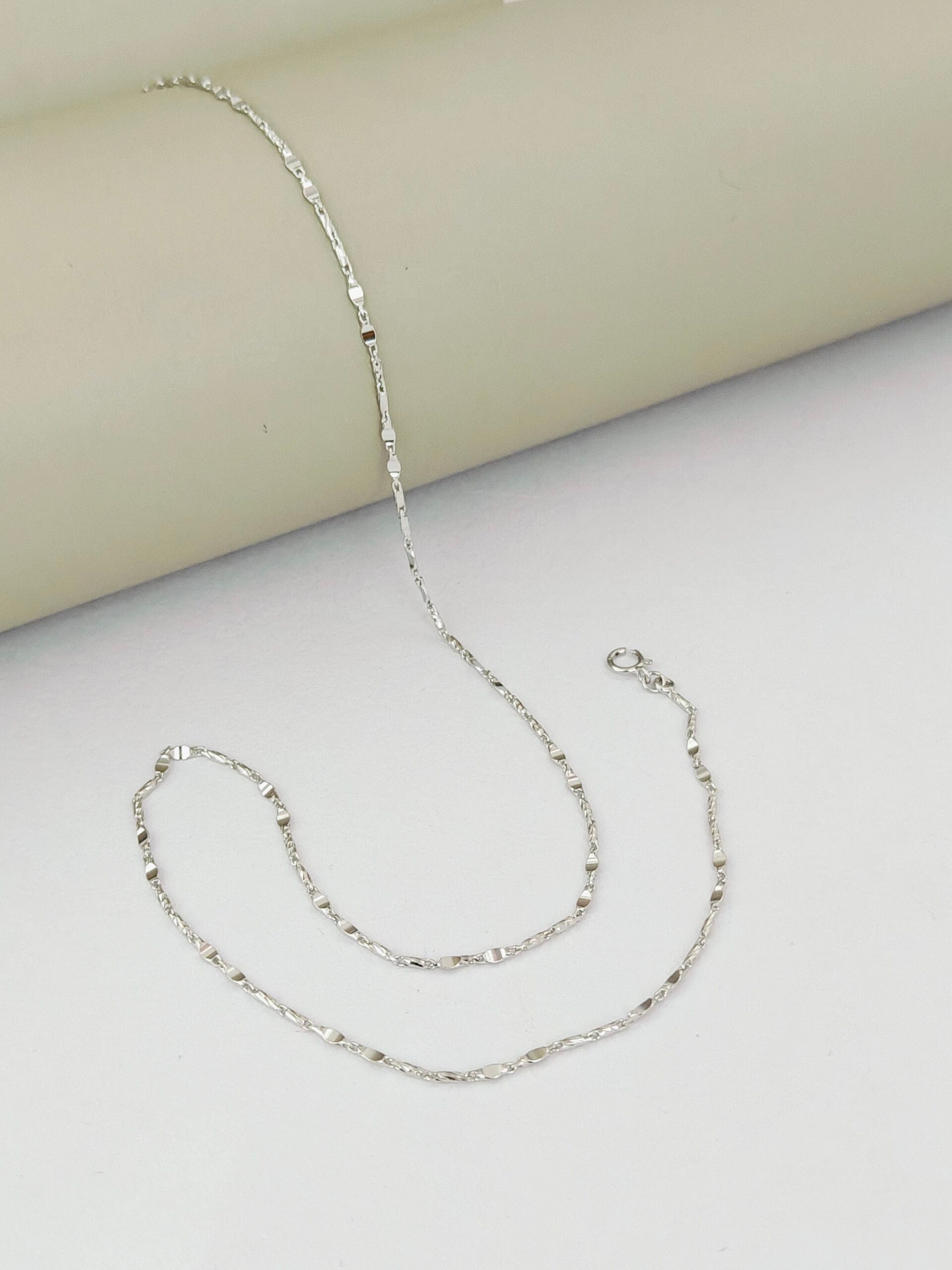 Silver chain necklace on a light gray surface
