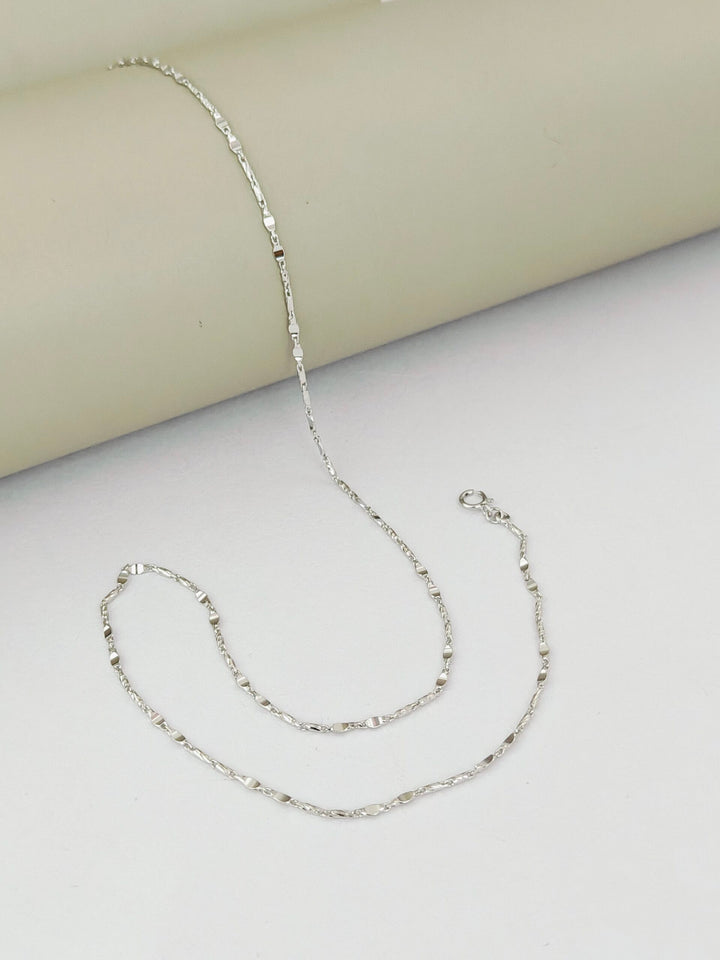 Silver chain necklace on a light gray surface