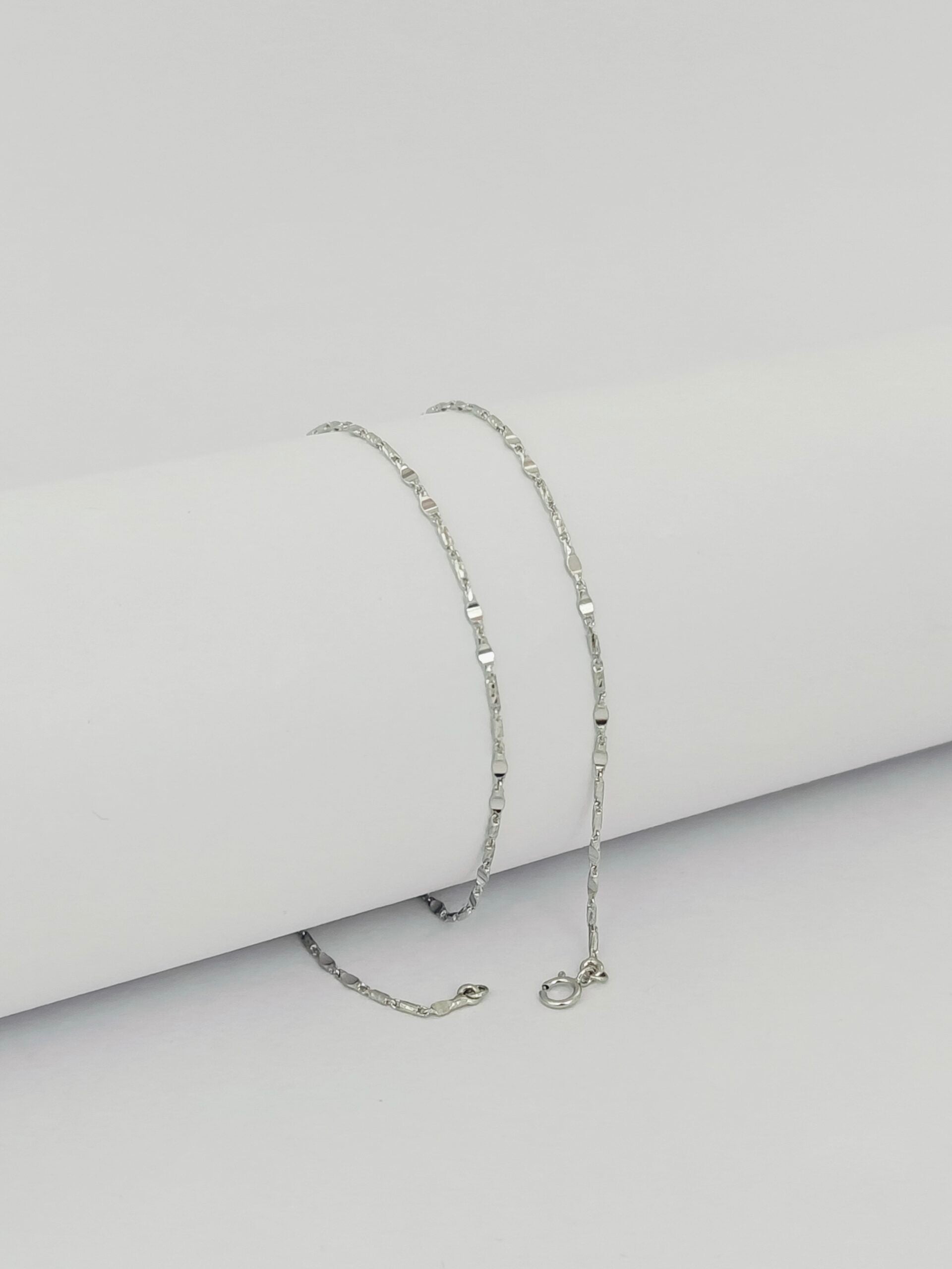 Silver chain necklace on a light gray background
