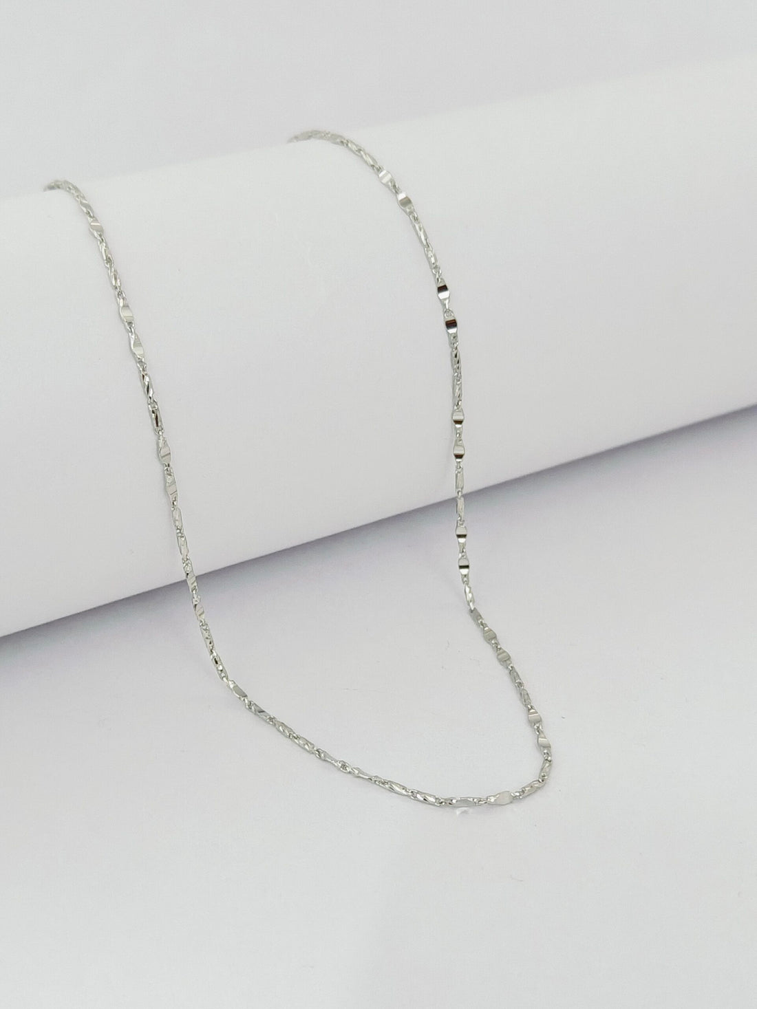 Silver necklace on a light gray background