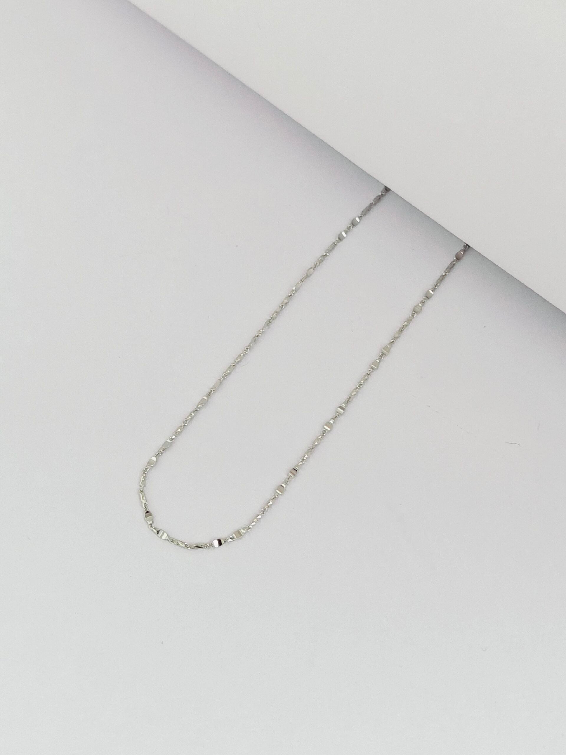 Silver chain necklace on a light gray surface