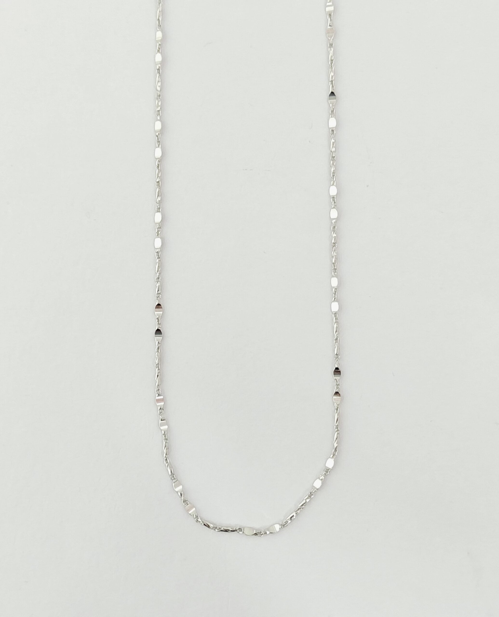 Silver chain necklace on a light gray background