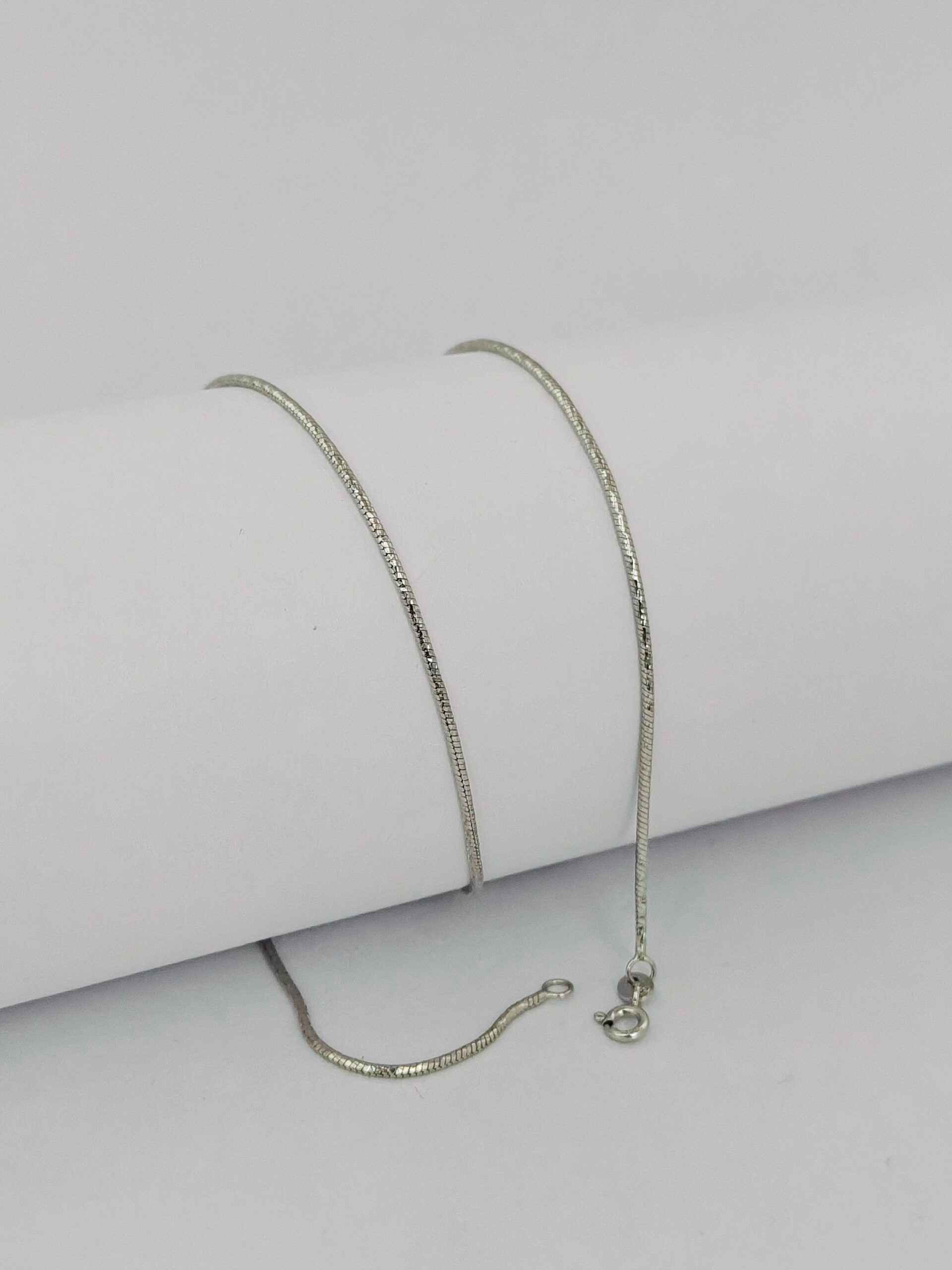 Silver chain necklace on a light gray background