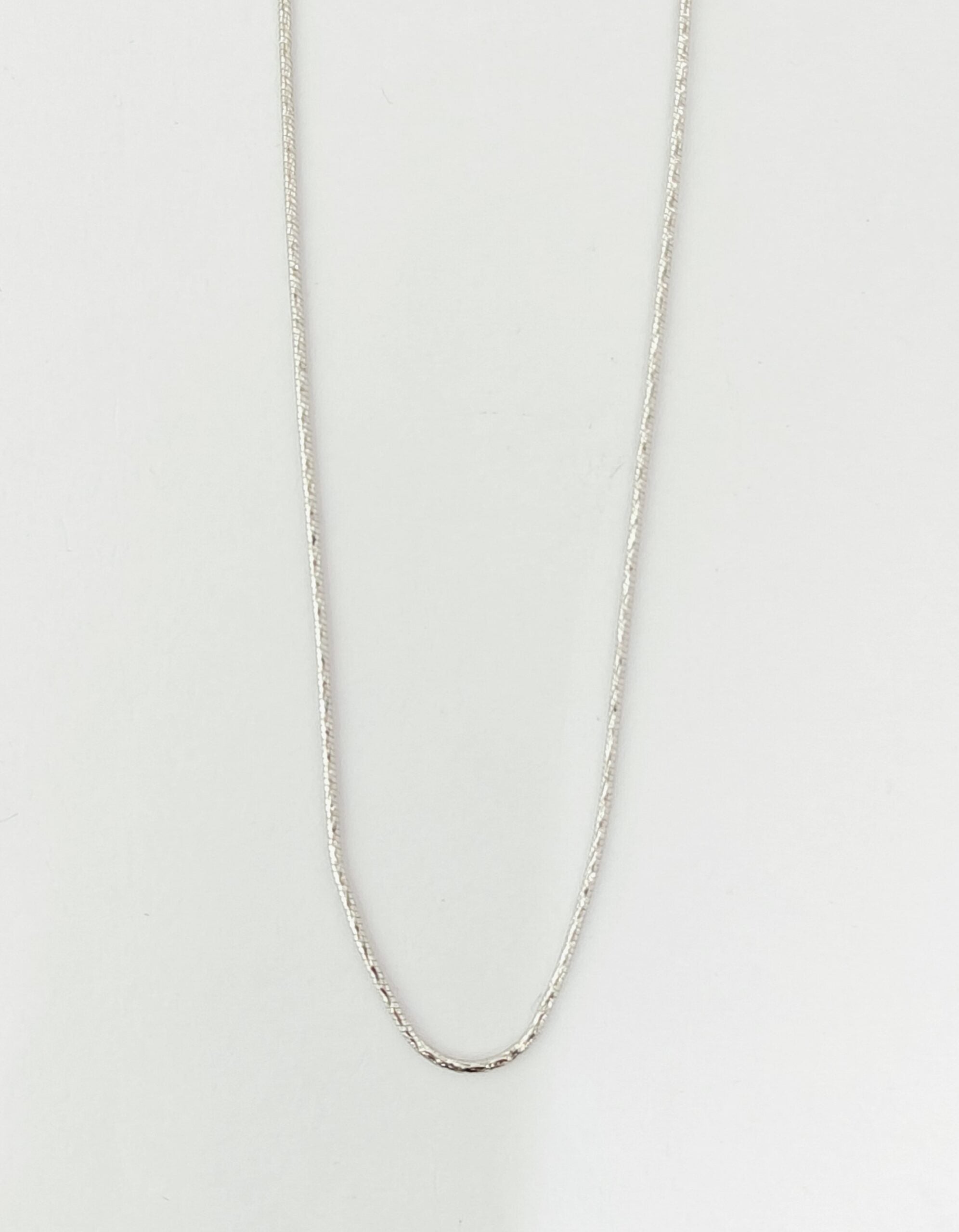Silver chain necklace on a light gray background