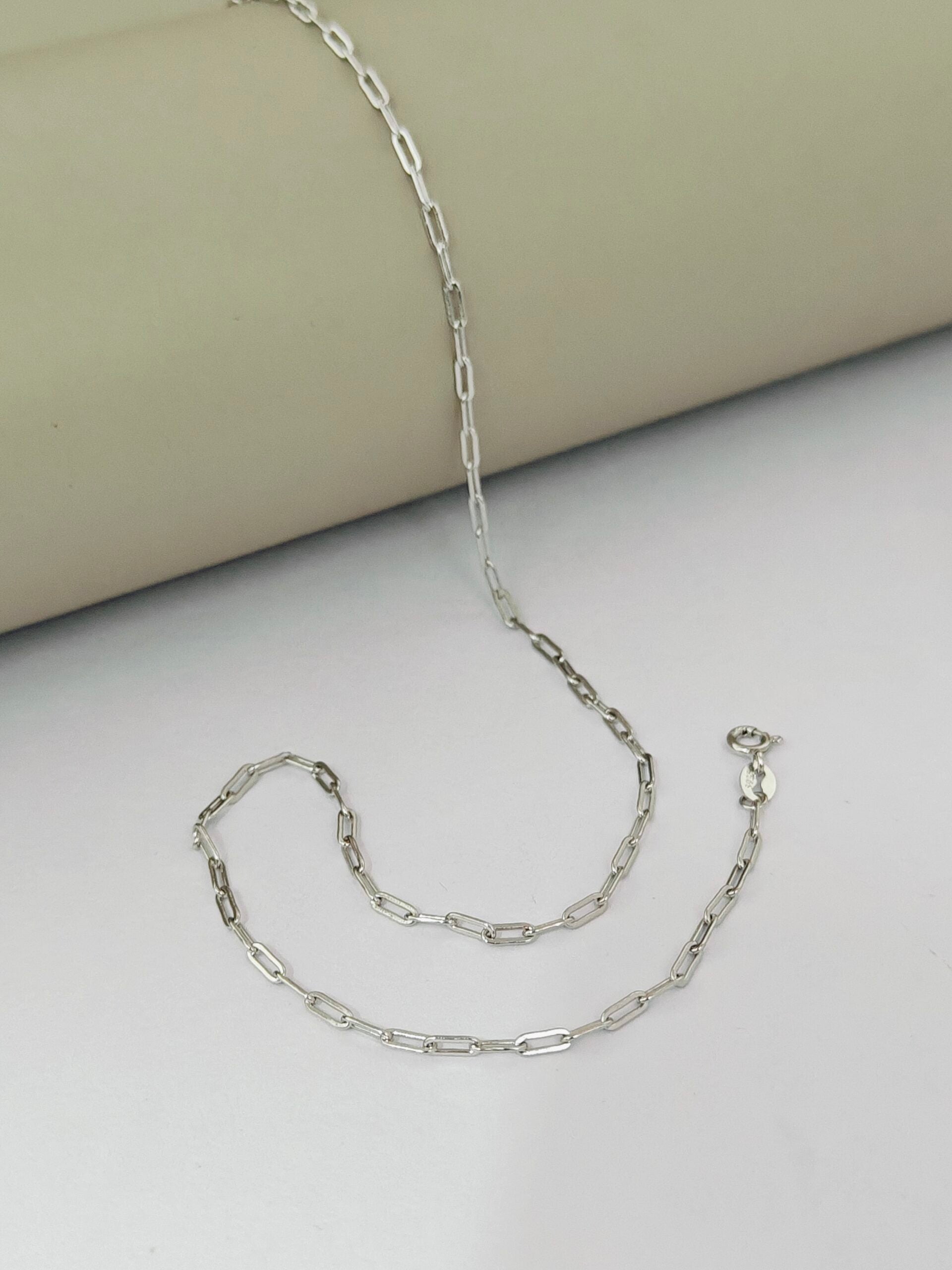 Silver chain necklace on a light gray surface