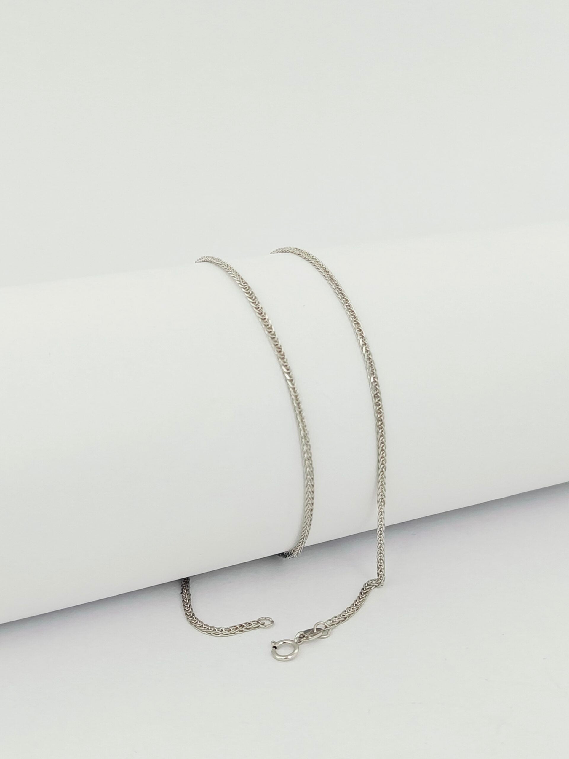 Silver chain necklace on a light gray background