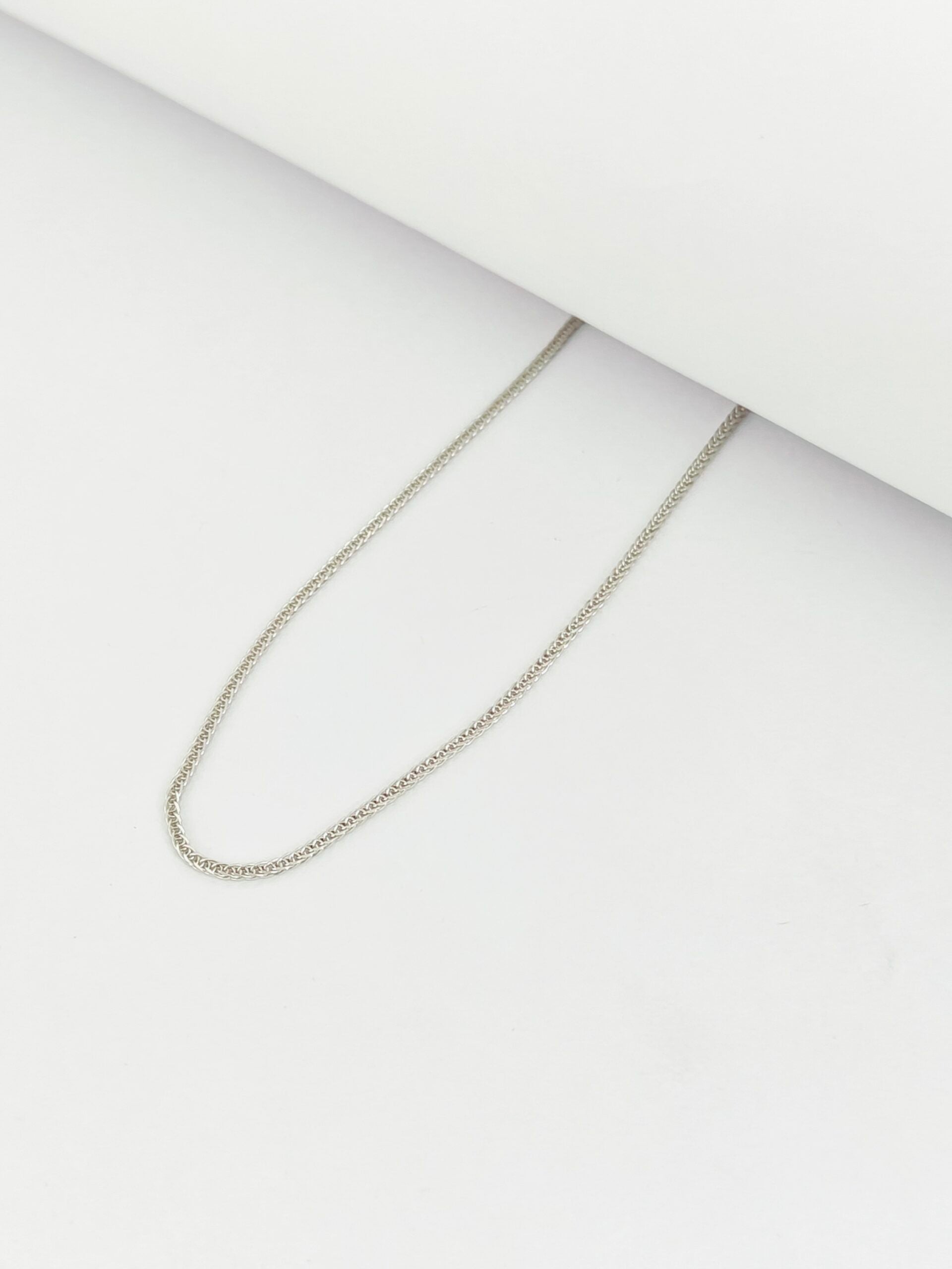 Silver chain necklace on a light gray background
