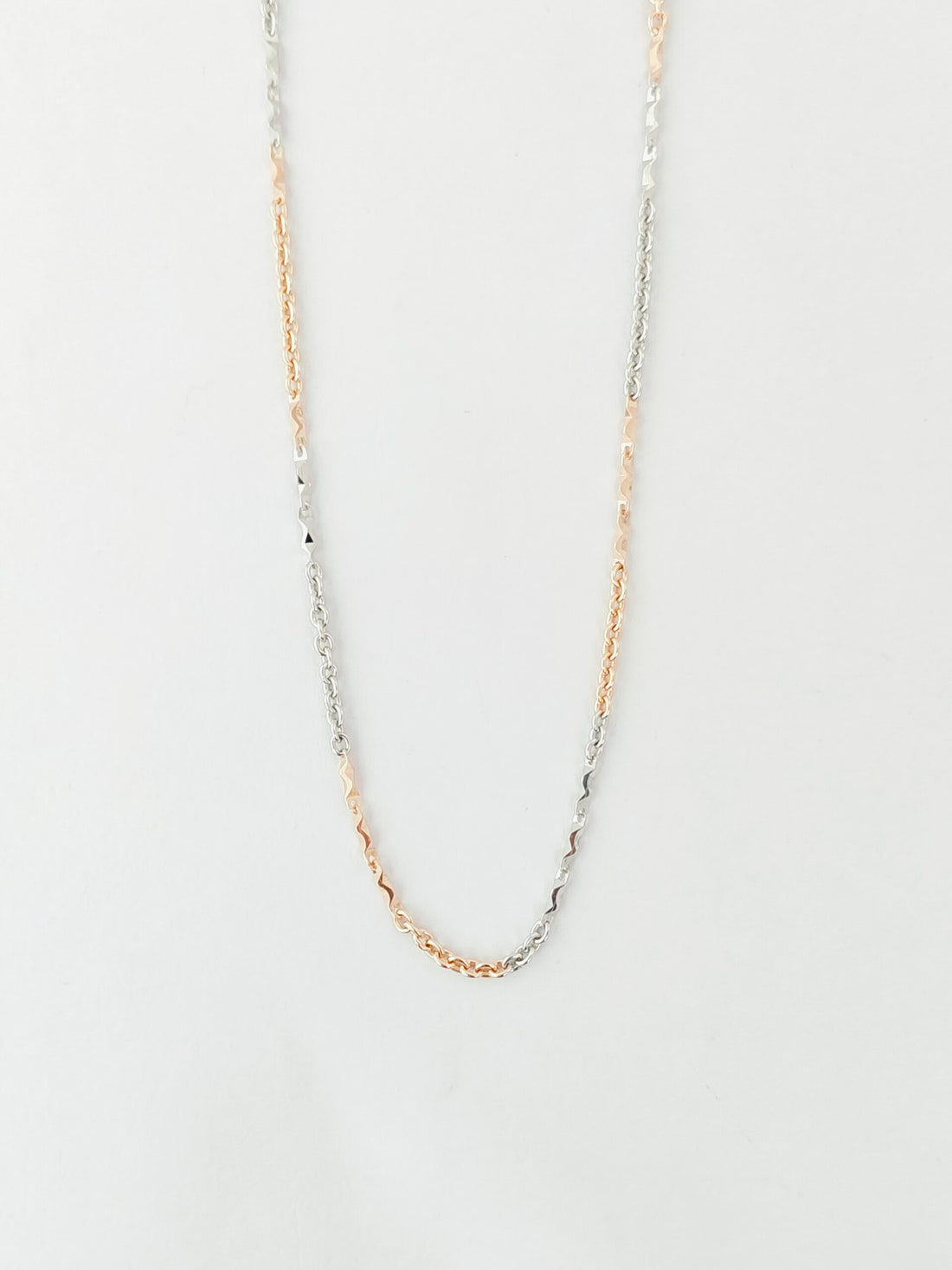 Gold chain necklace on a light gray background