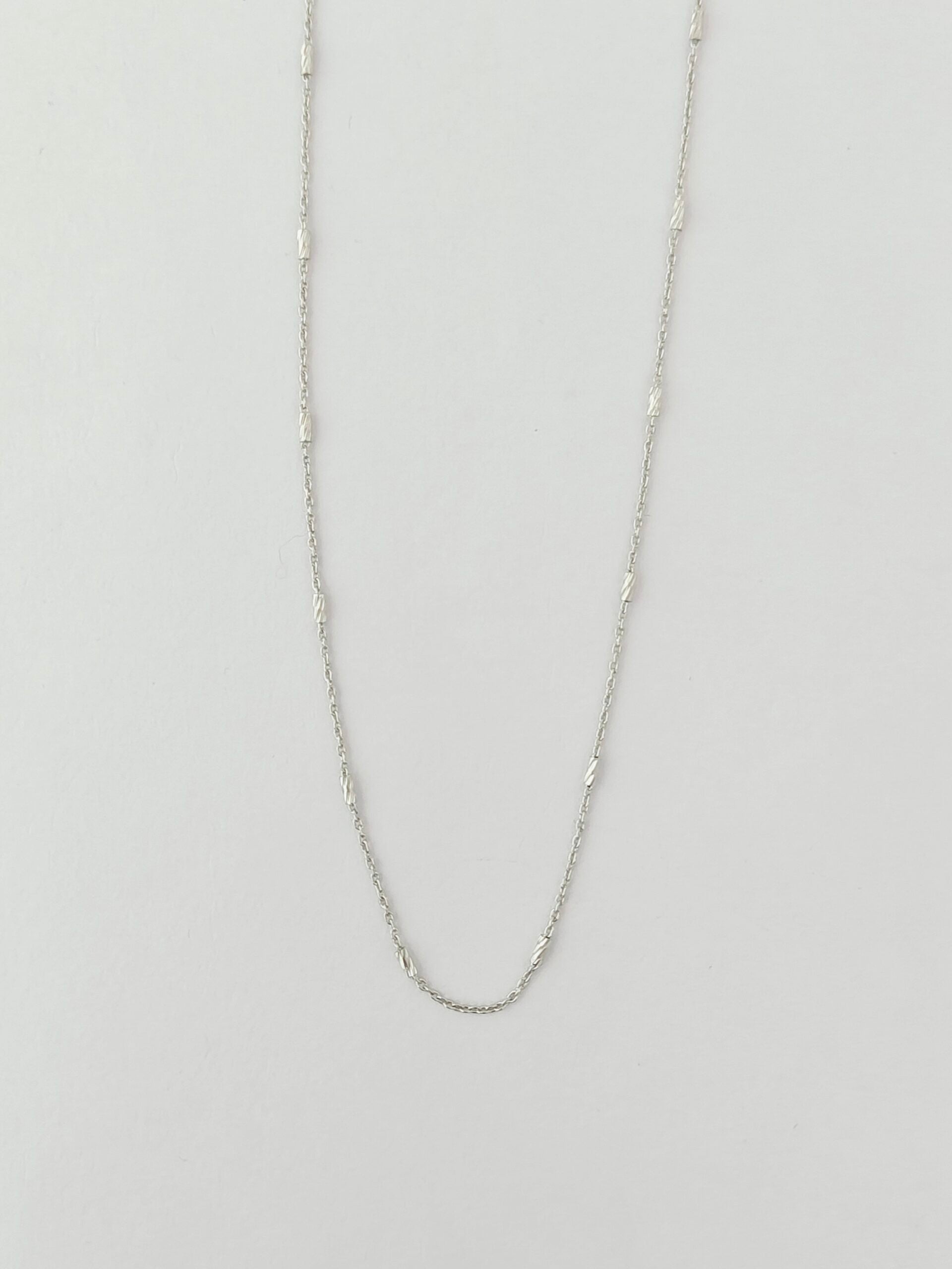 Silver chain necklace on a light gray background