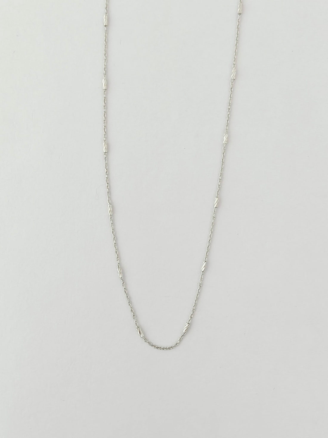 Silver chain necklace on a light gray background