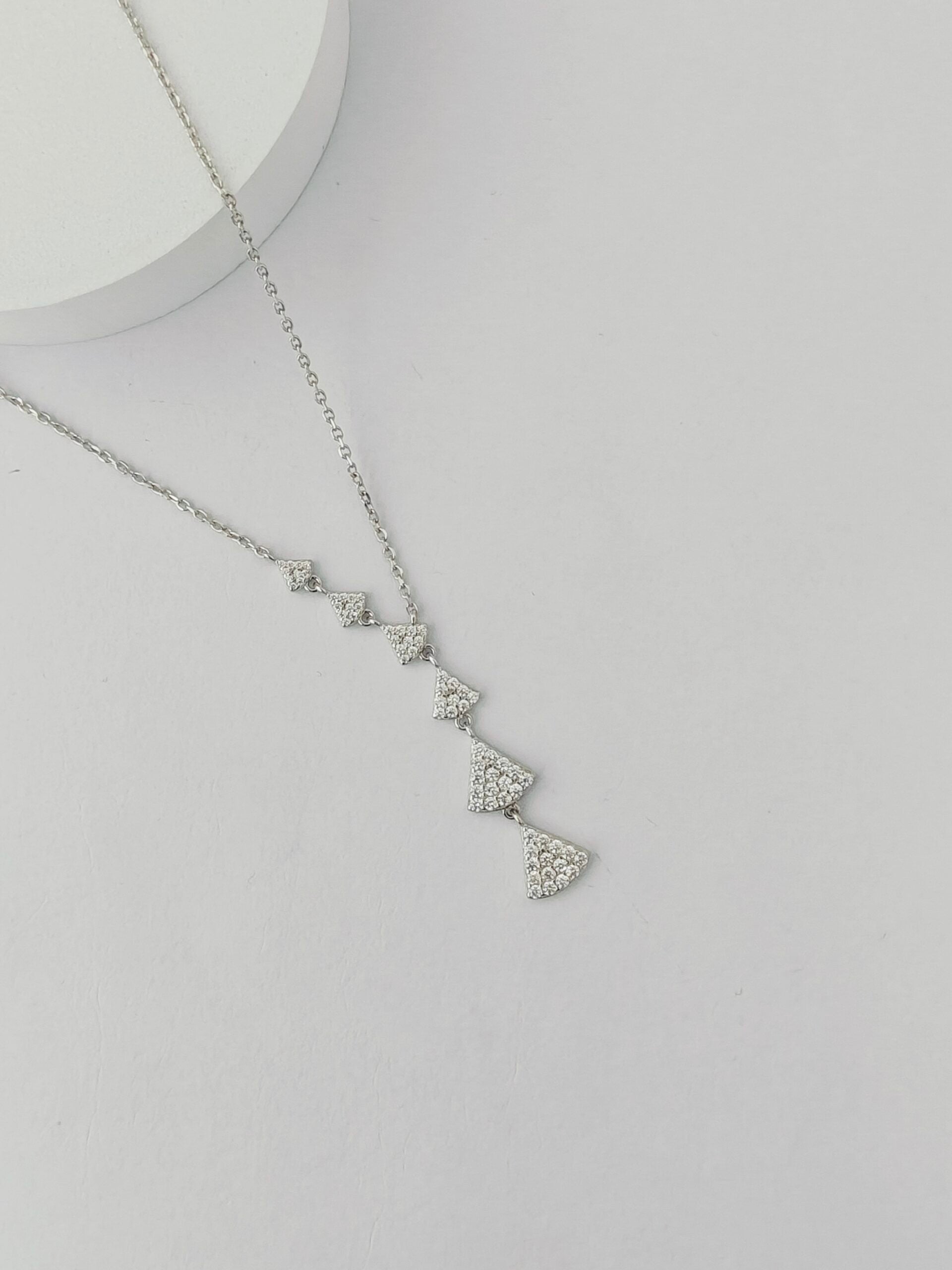 Silver necklace with heart-shaped pendant on a light gray background