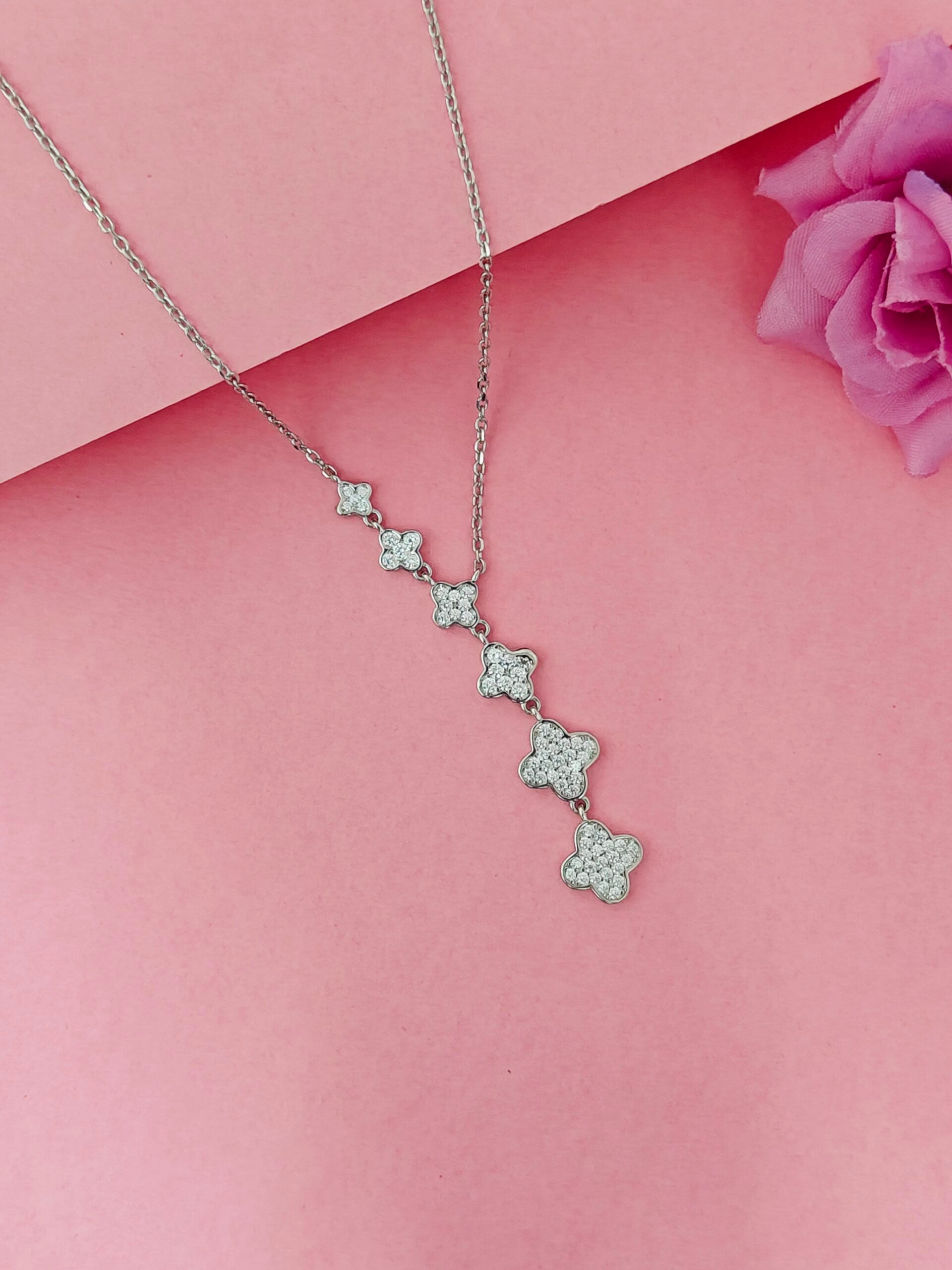 Silver necklace with star-shaped pendants on a pink background