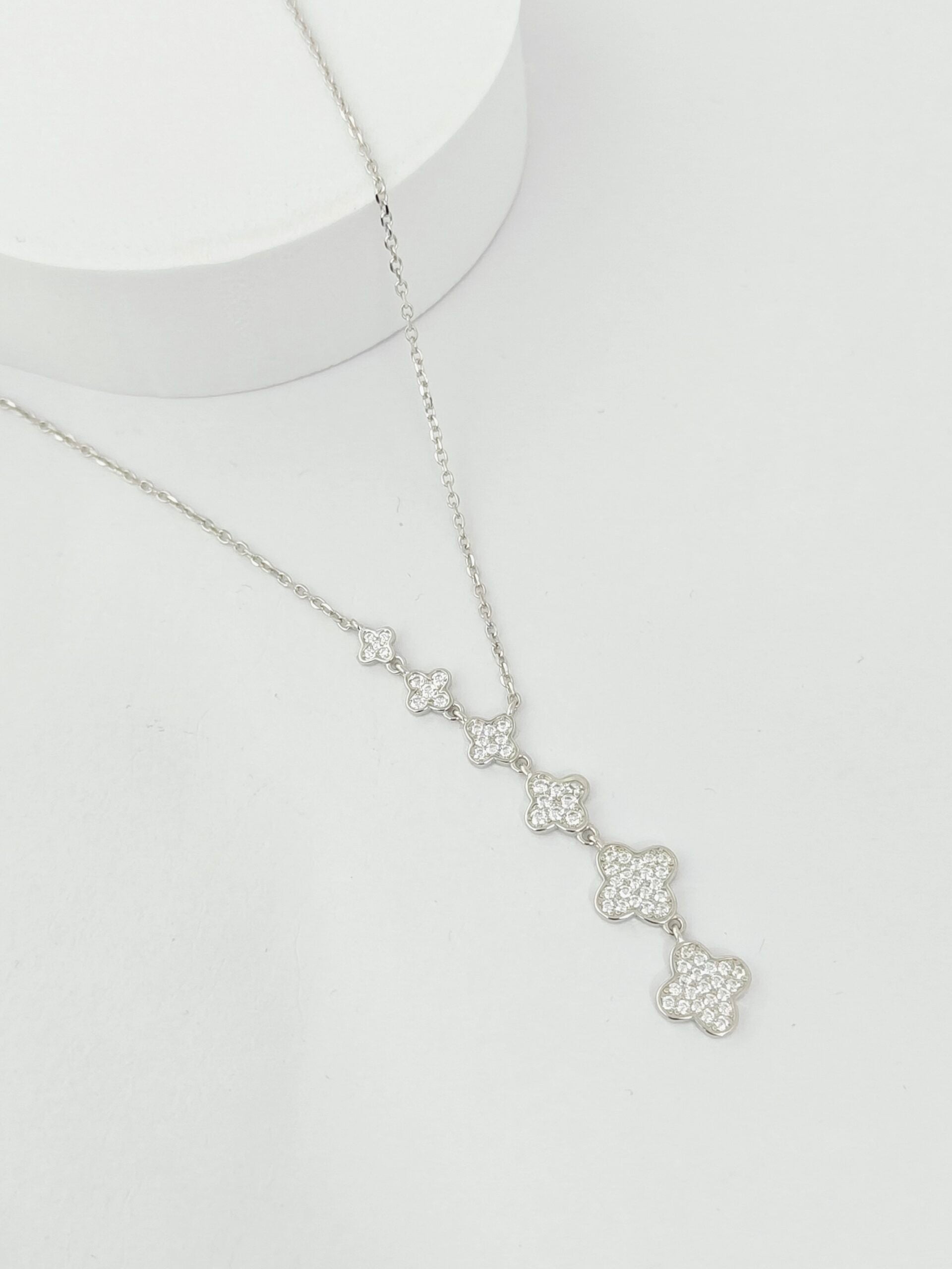 Silver necklace with floral pendant on a light gray background