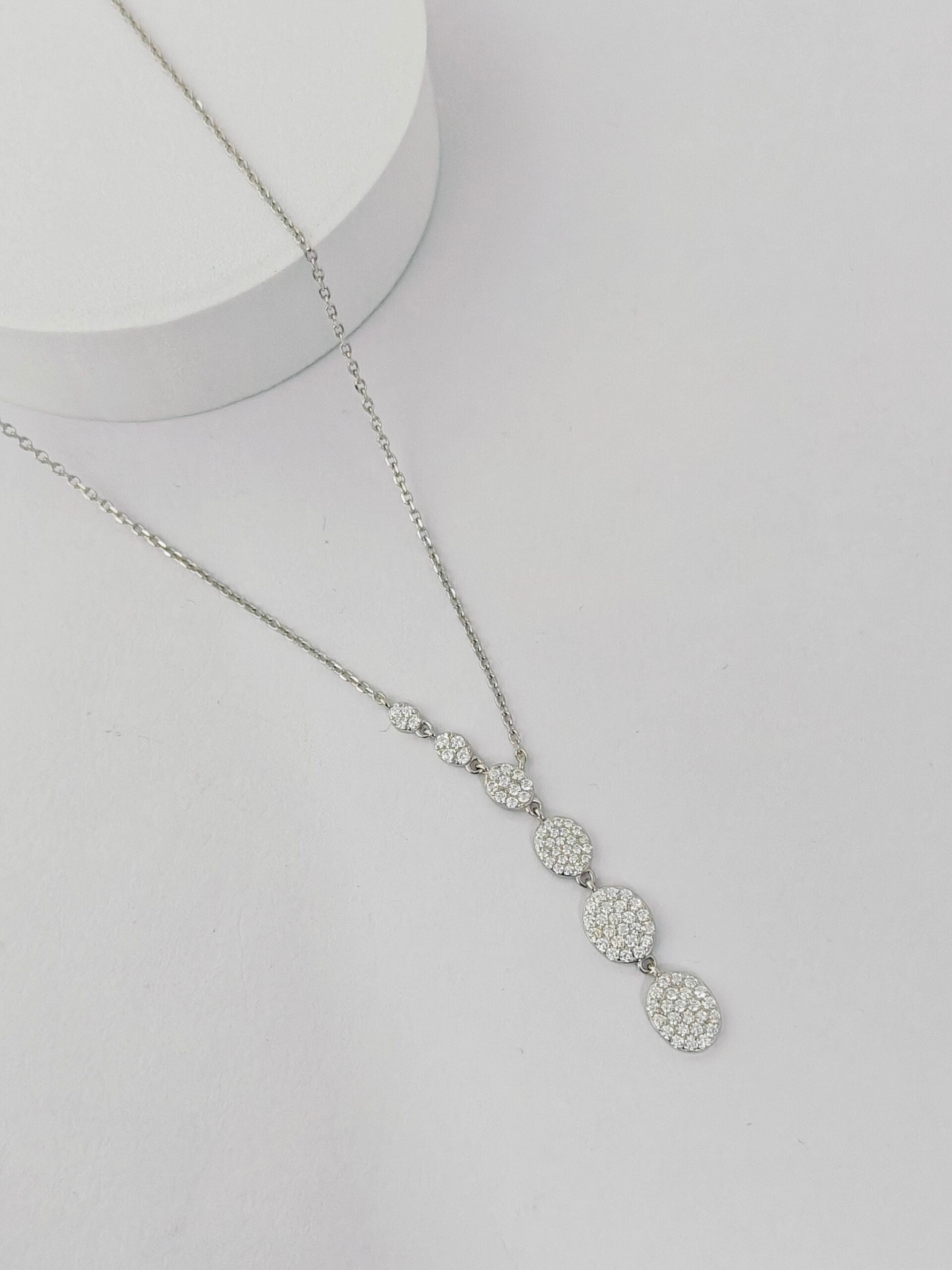 Silver necklace with three circular pendants on a light gray background