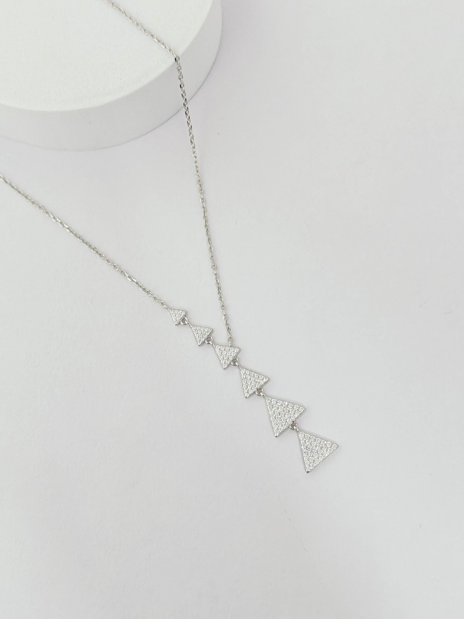 Silver necklace with triangular pendants on a light gray background