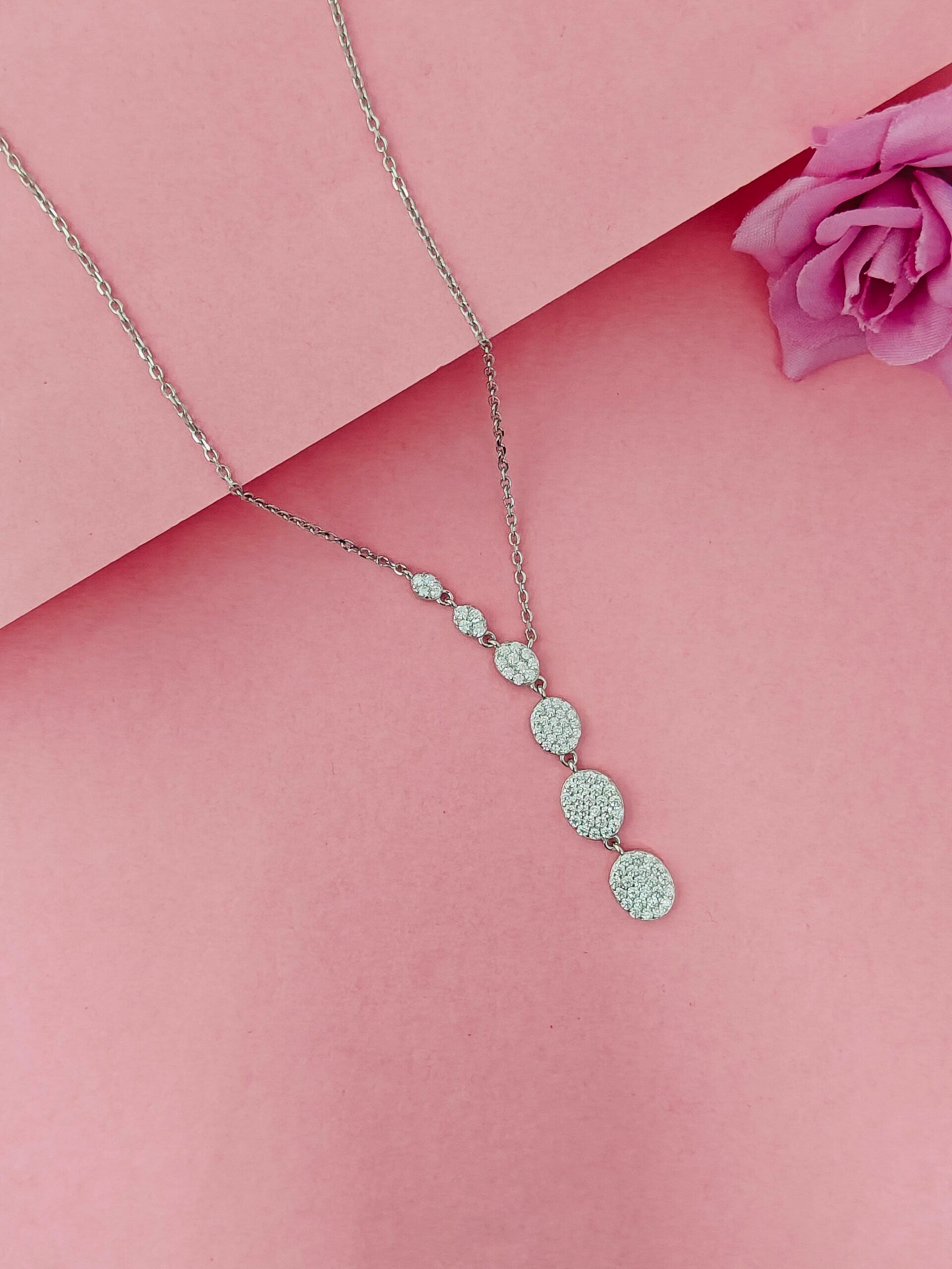 Necklace with circular pendants on a pink background