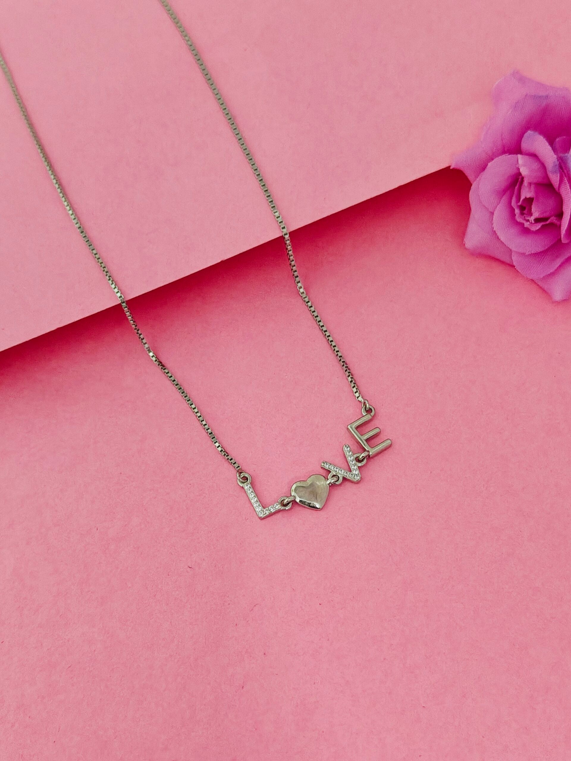 Necklace with 'LOVE' pendant on a pink background