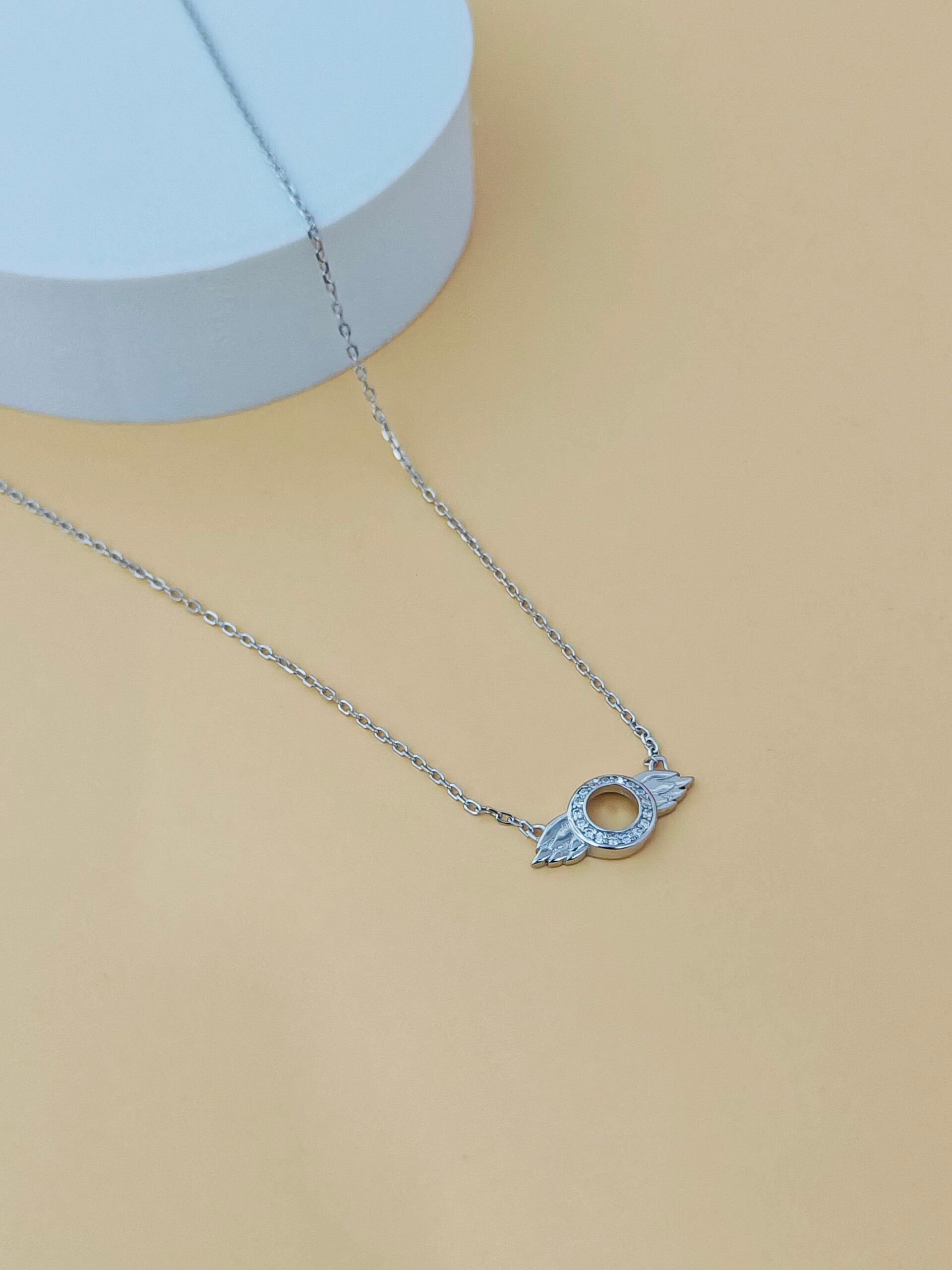 Silver necklace with a pendant on a beige background