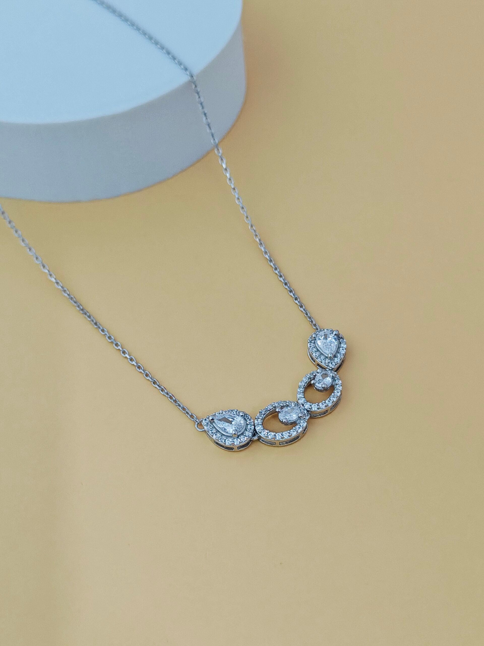 Silver necklace with heart-shaped pendants on a beige background