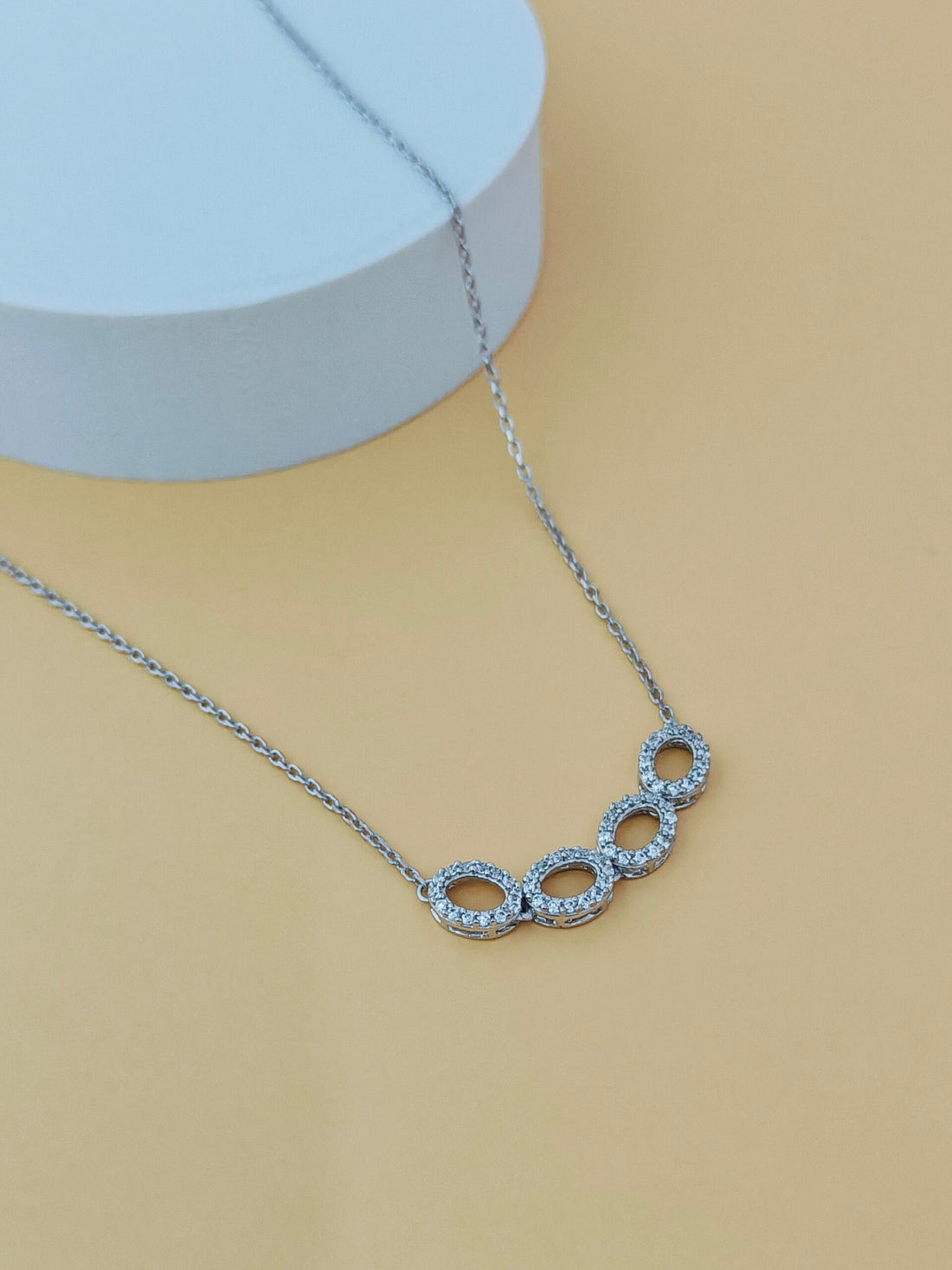 Silver necklace with circular pendant on a beige background