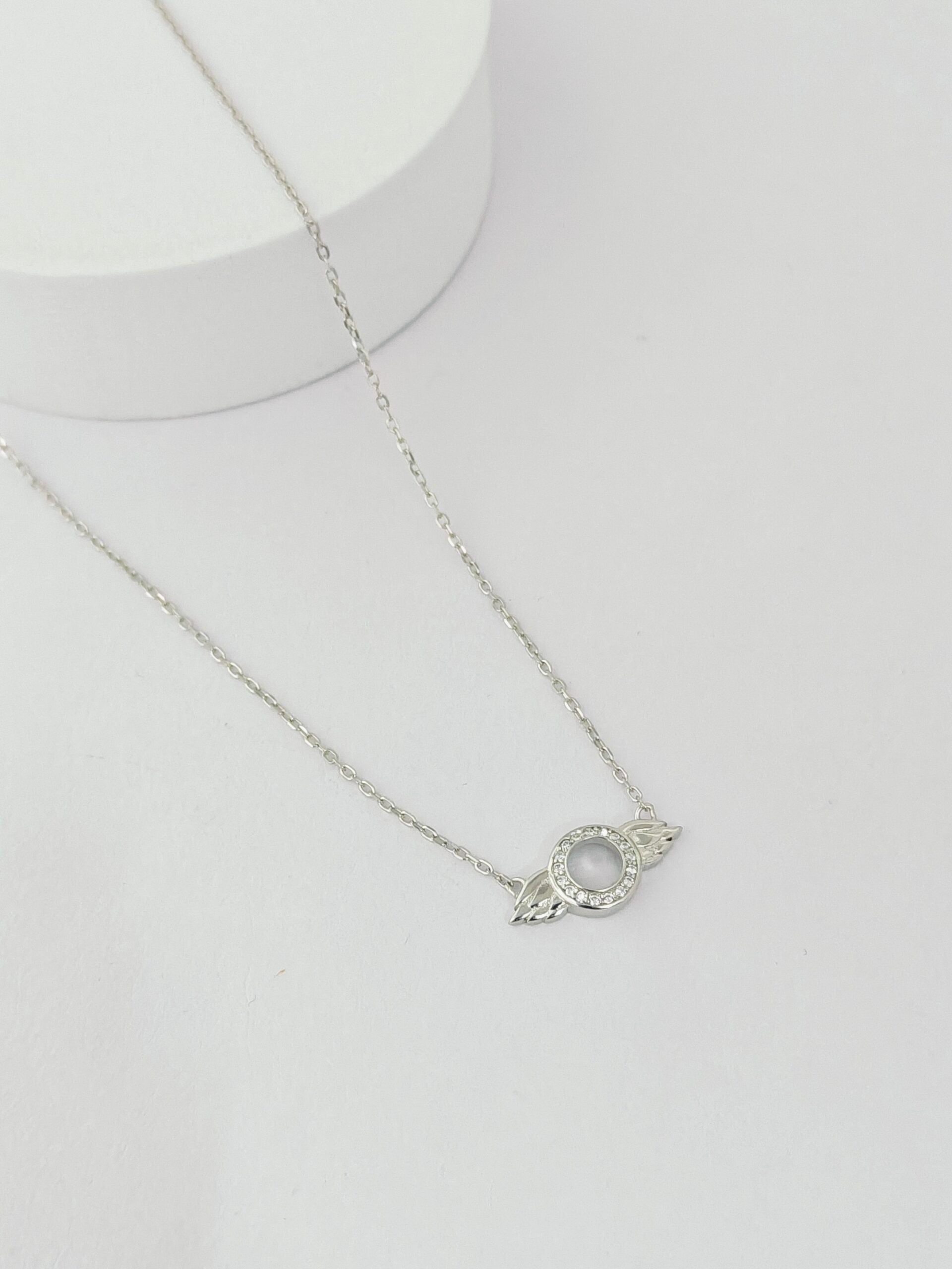 Silver necklace with a circular pendant on a white background