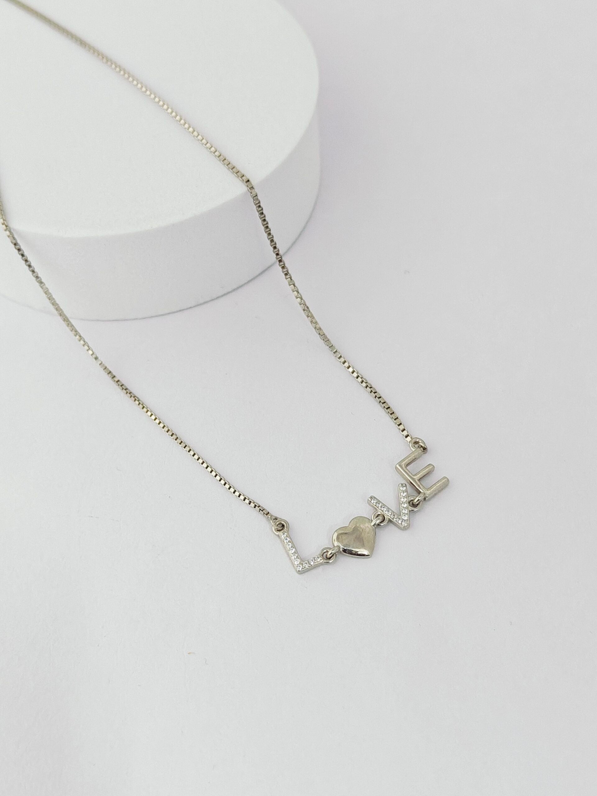 Silver necklace with 'LOVE' pendant on a white background