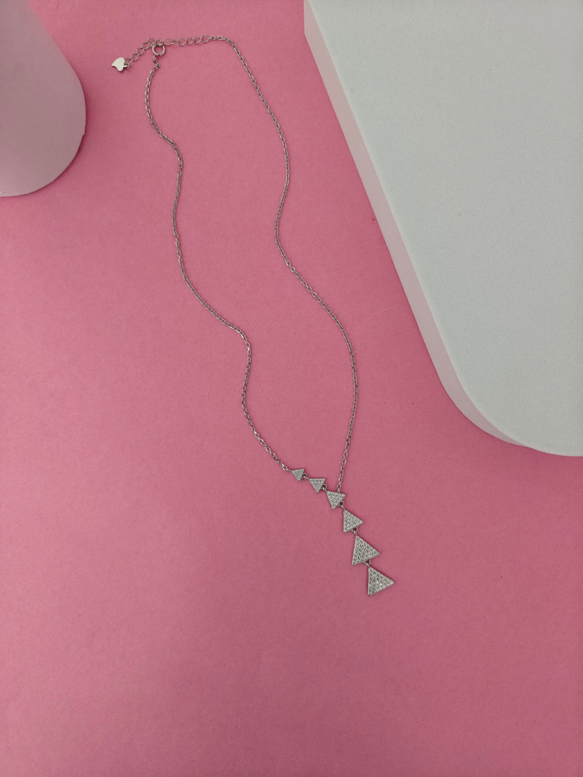 Necklace with triangle pendants on a pink surface