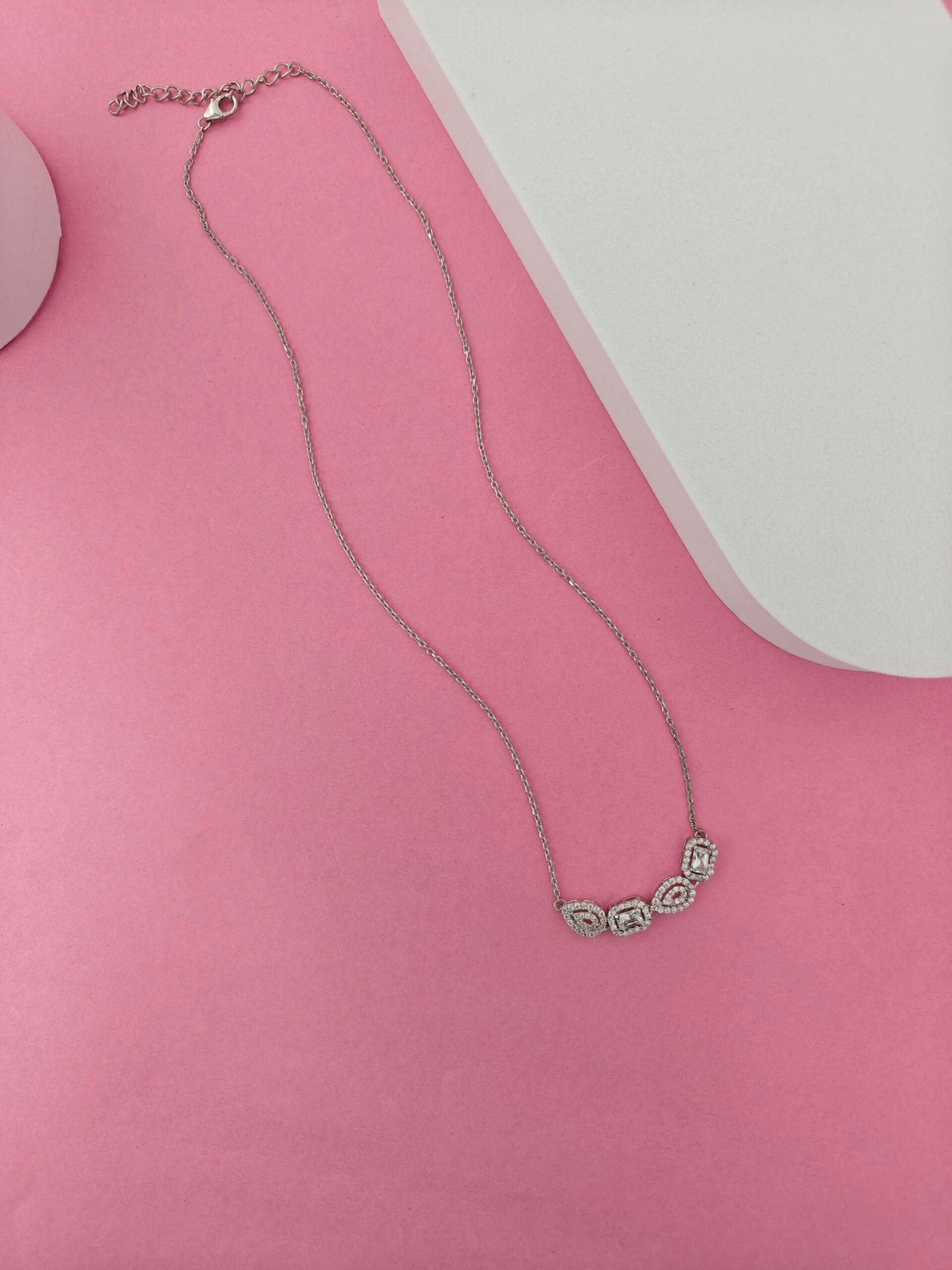 Necklace with green gemstones on a pink surface