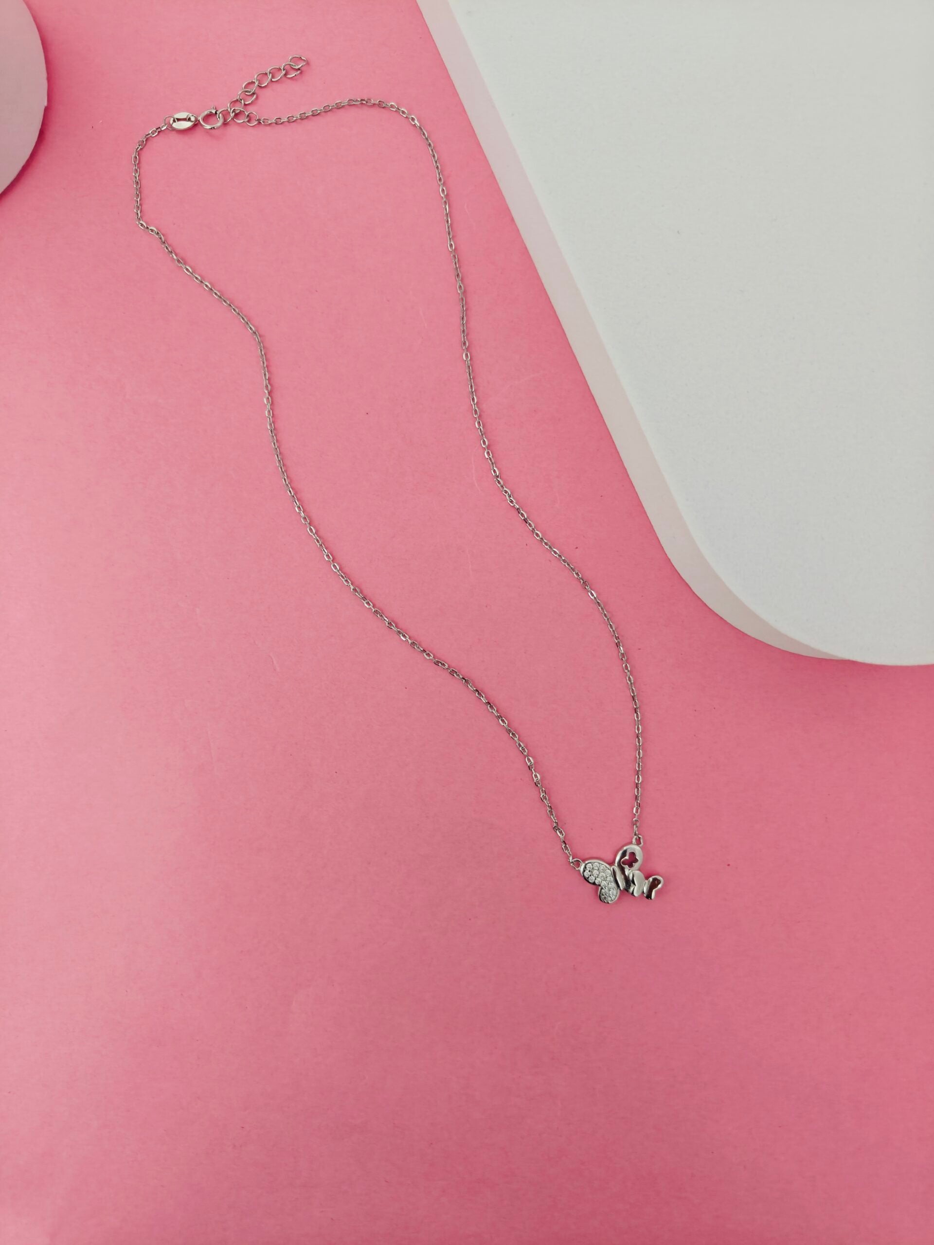 Butterfly necklace on a pink surface
