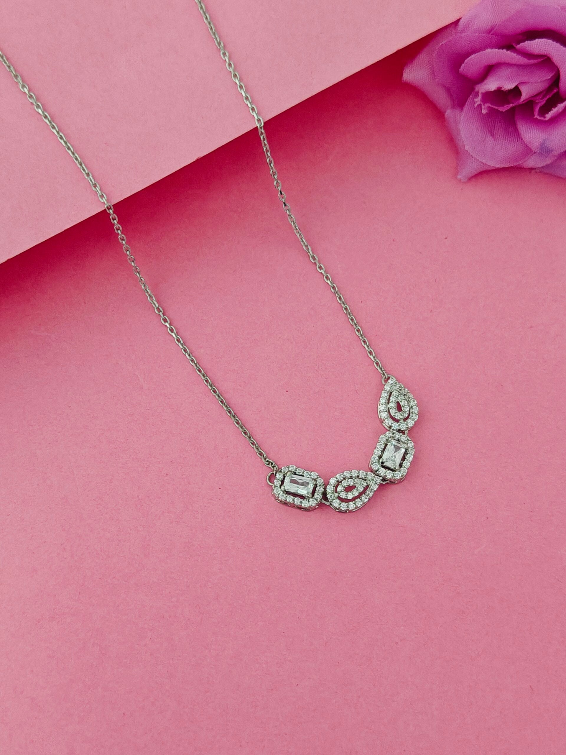 Silver necklace with gemstones on a pink background