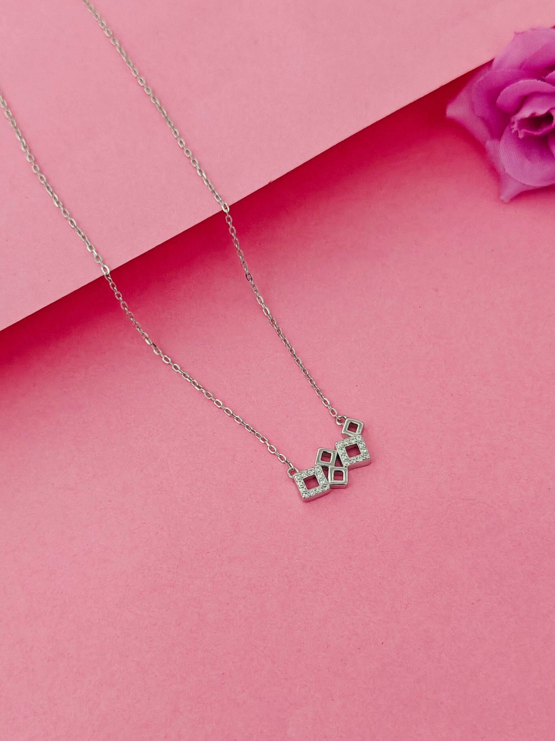 Necklace with a geometric pendant on a pink background