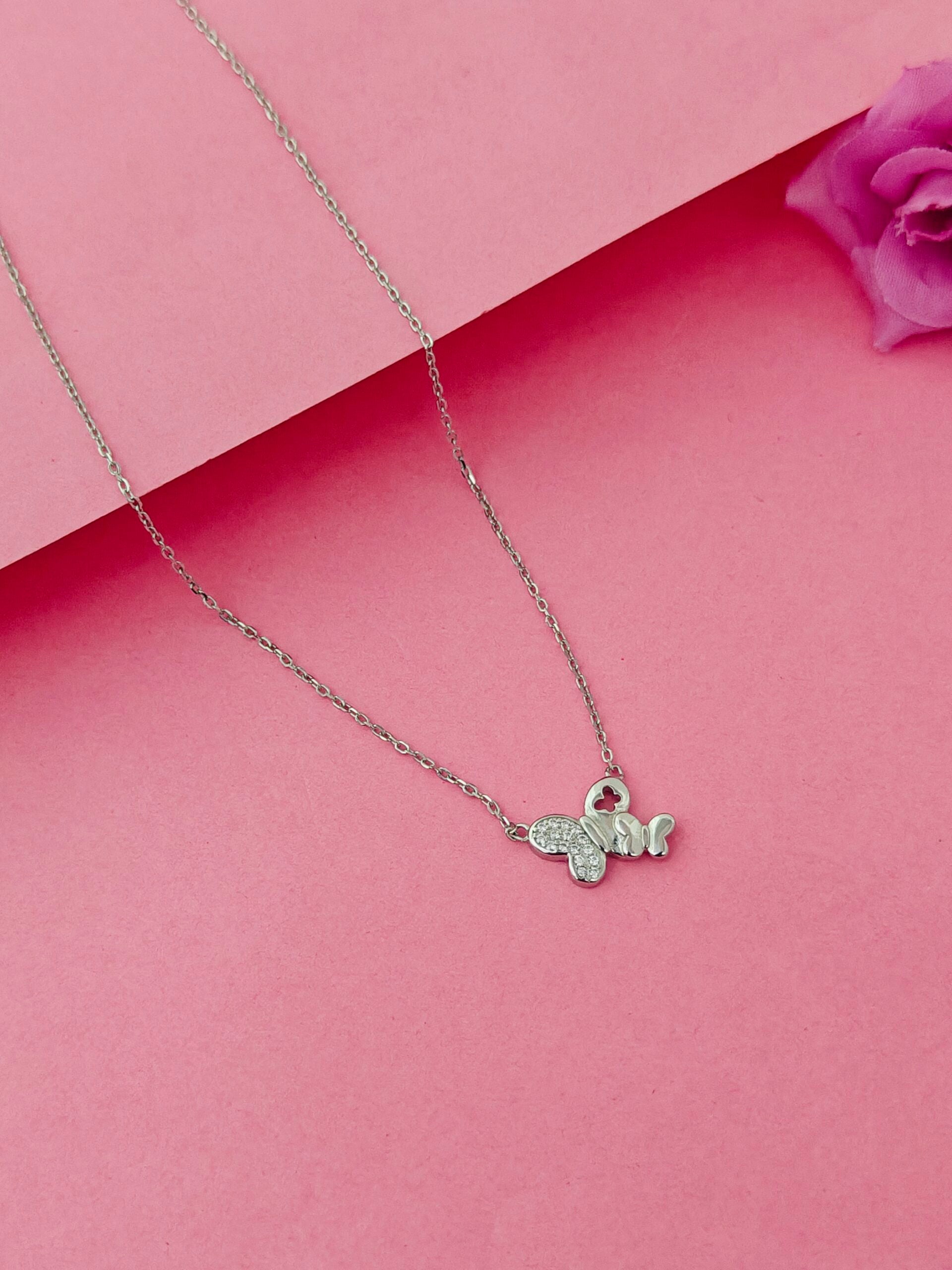 Silver necklace with a bee pendant on a pink background