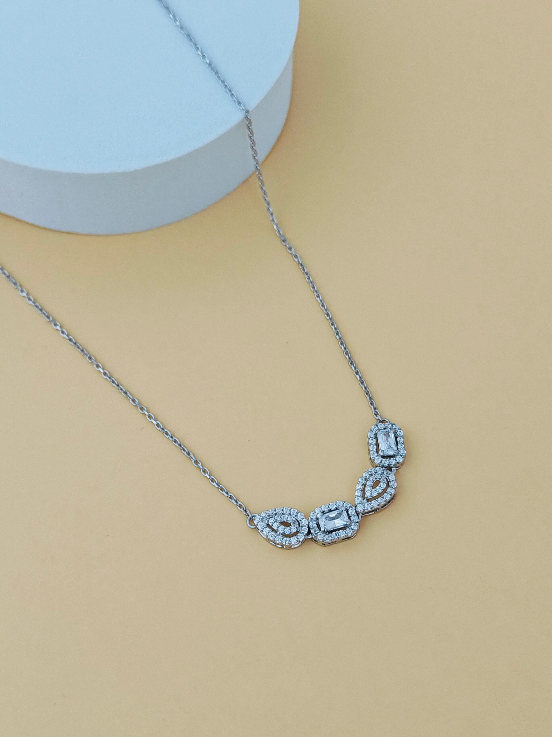 Silver necklace with gemstones on a mannequin bust against a beige background